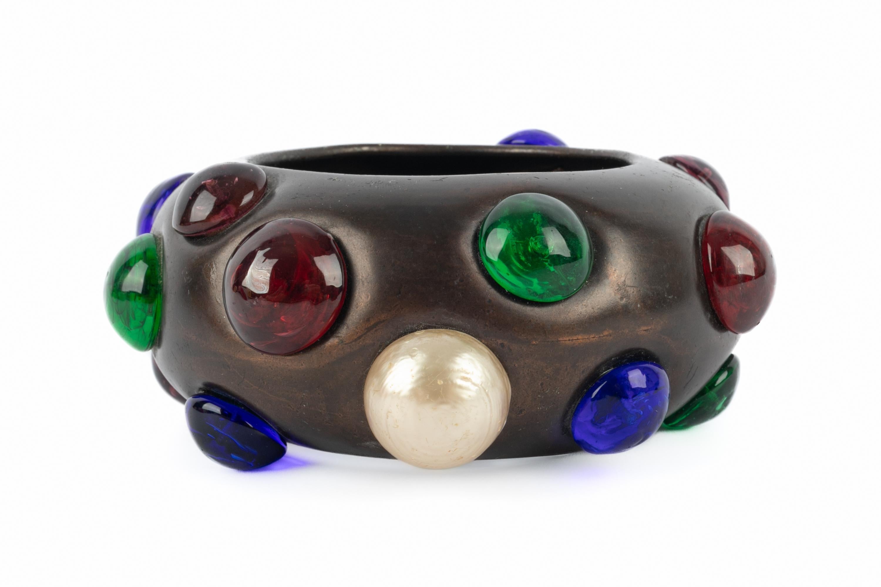 Yves SAINT LAURENT - Bracelet bangle en métal bruni orné de cabochons en pâte de verre et de perles. Une collection de haute couture des années 1980. Œuvre de l'Atelier Robert Goossens.

Condit :
Bon état

Dimensions :
Tour de poignet : 20