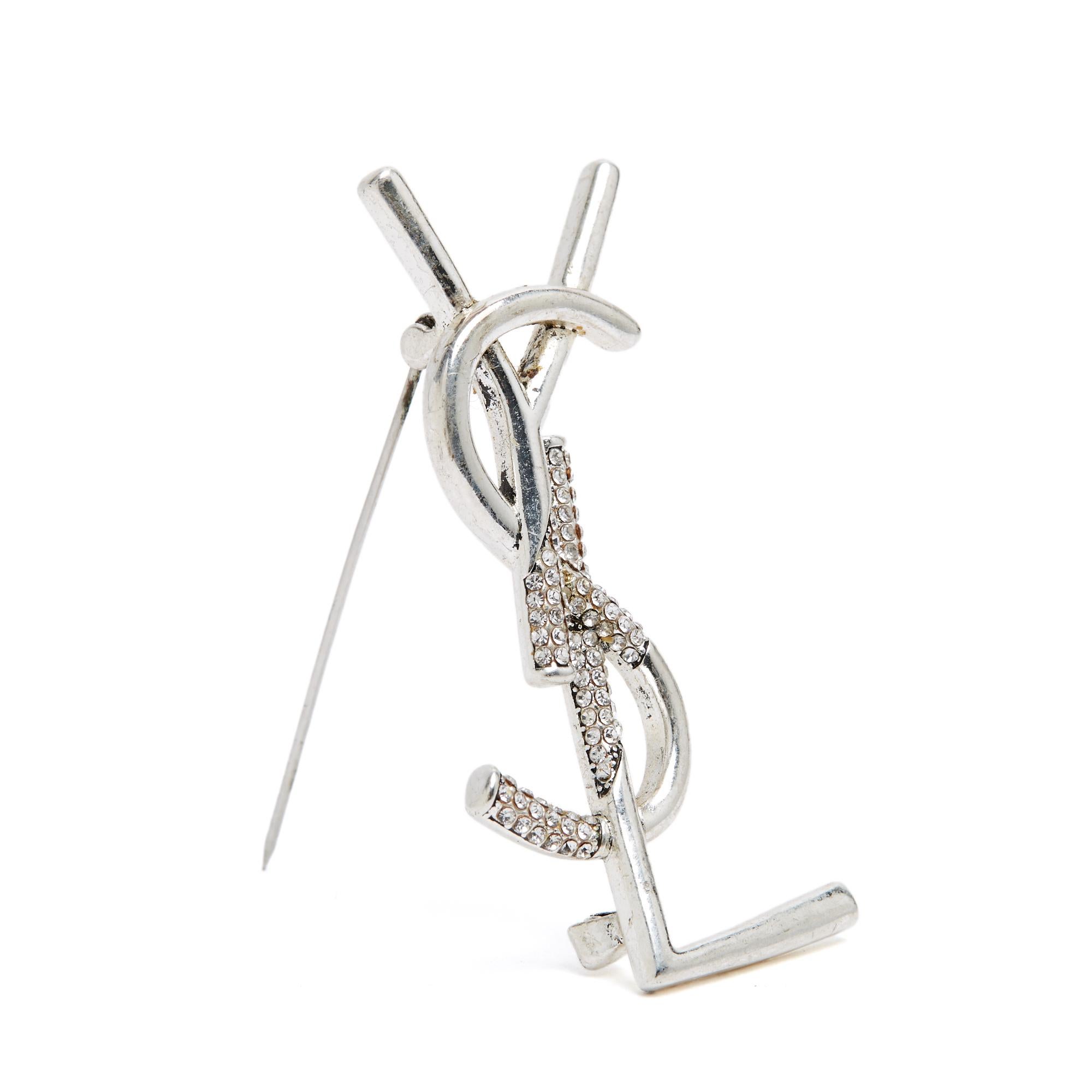 Broche Saint Laurent Cassandre o YSL, probablemente de la colección 2024, de metal plateado envejecido con incrustaciones de brillantes, 2,5 cm de ancho x 5 cm de alto. El pegamento de strass está ligeramente amarilleado, pero esto es invisible a