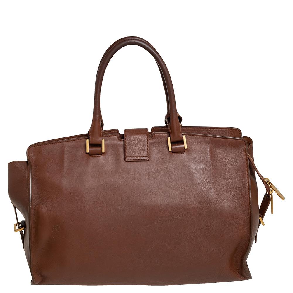 This classy Cabas Y-Ligne tote coming from Saint Laurent will adorn your look in the most stylish ways. It is crafted from leather in a brown hue featuring two rolled handles. This tote comes with a fabric-lined interior along with brand labeling