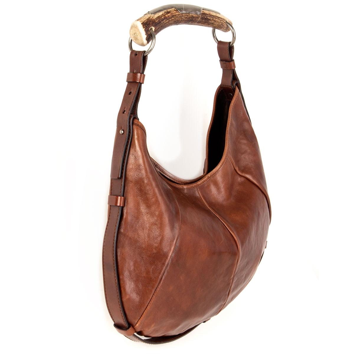 100% authentic Yves Saint Laurent Mombasa Medium shoulder bag in brown calfskin with horn handle featuring silver-tone hardware. Opens with a magnetic button and is lined in espresso brown suede with one zipper pocket against the back. Has been