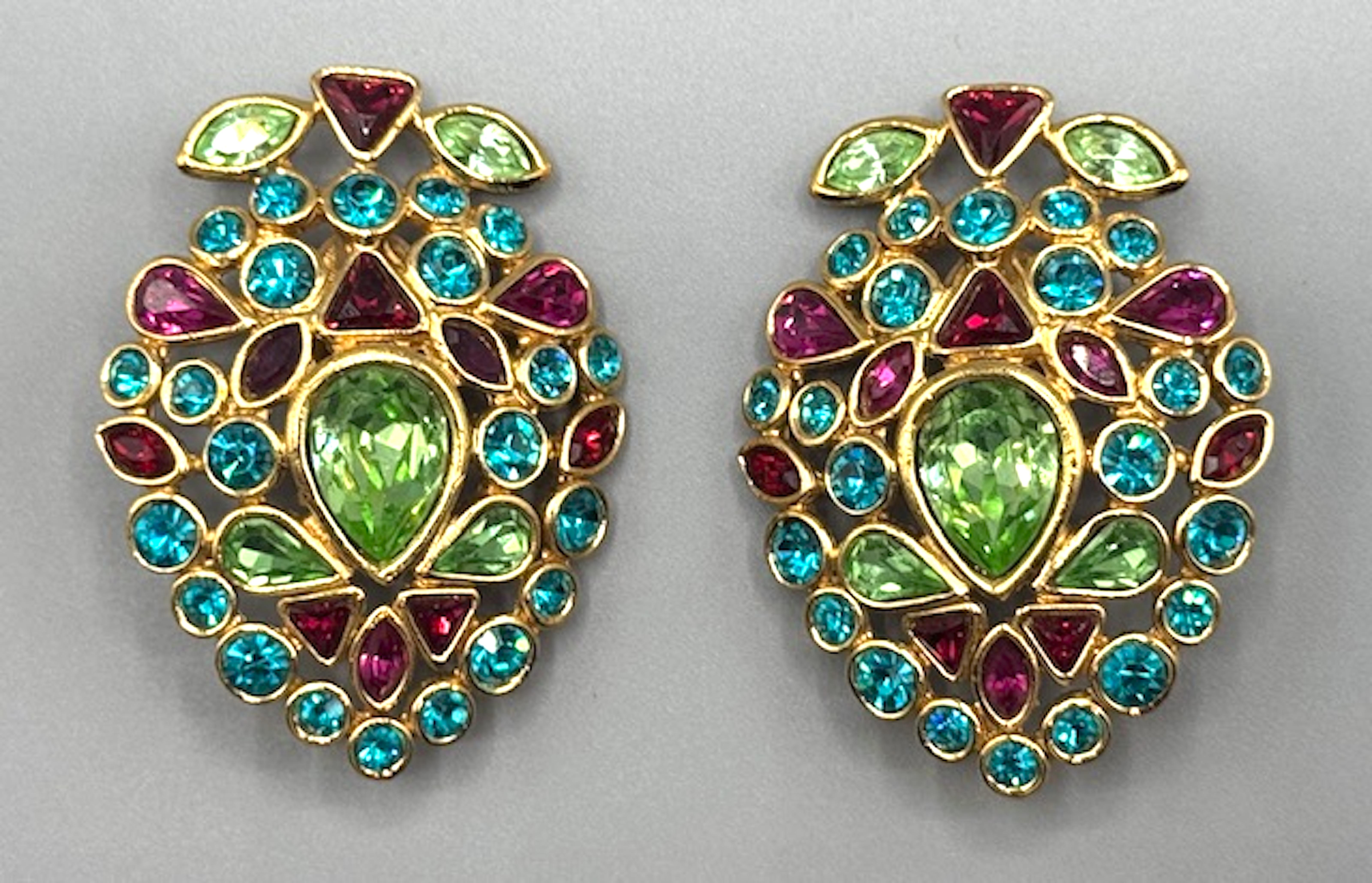 These Yves Saint Laurent clip earrings designed by Robert Goossens are a stunning example of 1980s high fashion jewelry. The bold use of fuchsia, teal, and light green rhinestones in a mix of cuts (round, pear, marquise, and trillion) reflects the