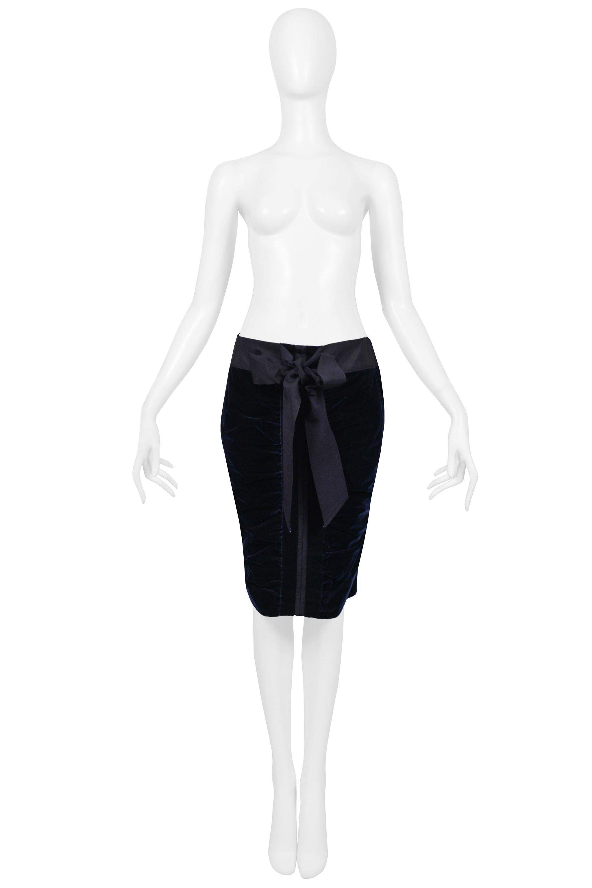 Resurrection is thrilled to offer a vintage Yves Saint Laurent by Tom Ford navy velvet skirt. The knee-length skirt features ruched velvet and ribbed ribbon detailing down the center front and back, bow at front waistband, pockets on left and right