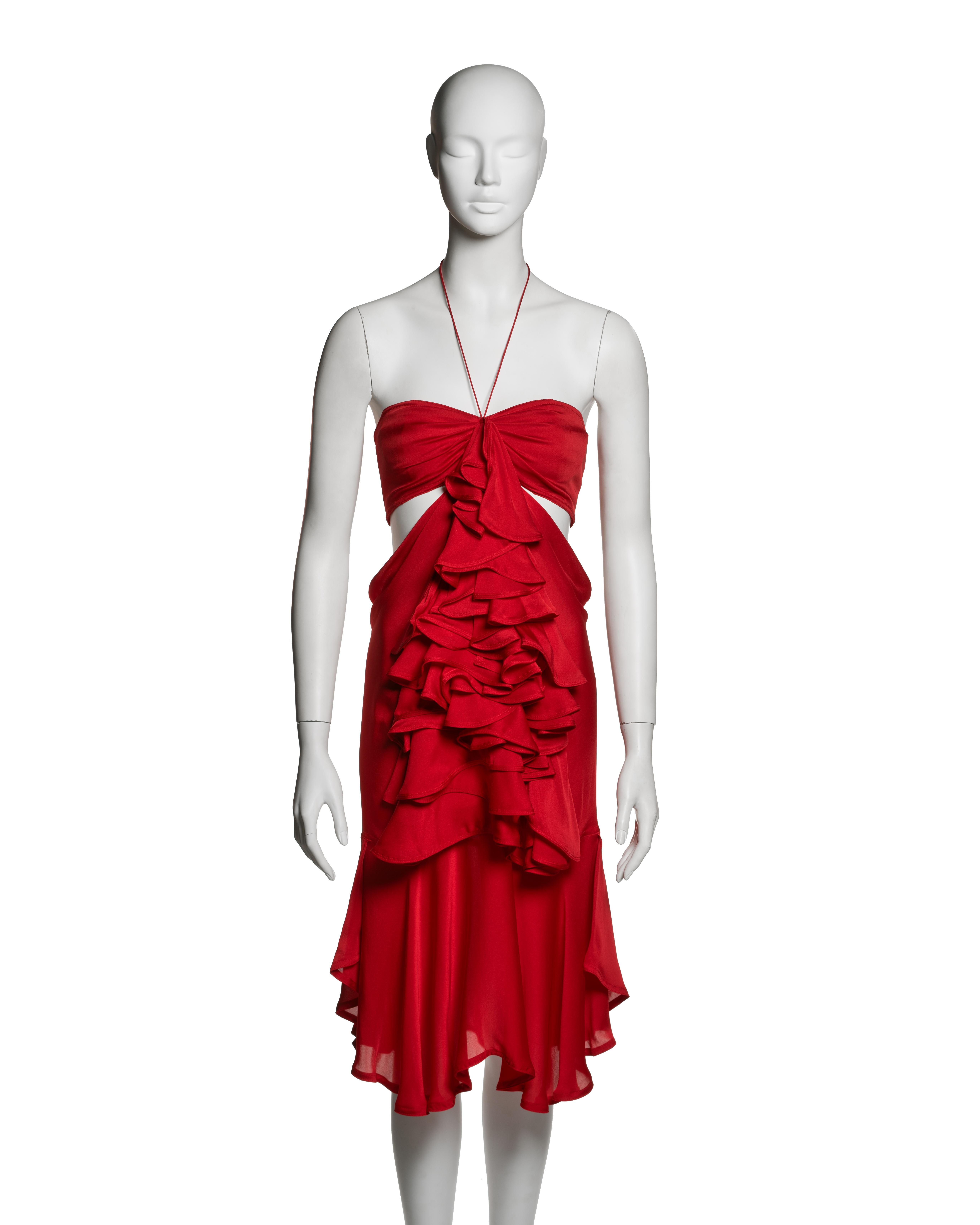 Sleeveless halterneck cocktail dress in crimson silk georgette by Yves Saint Laurent, designed by Tom Ford for the Fall-Winter 2003 collection. The bias-cut bodice is shaped with a central twist and vertical front cut-outs, drawing on Ford’s