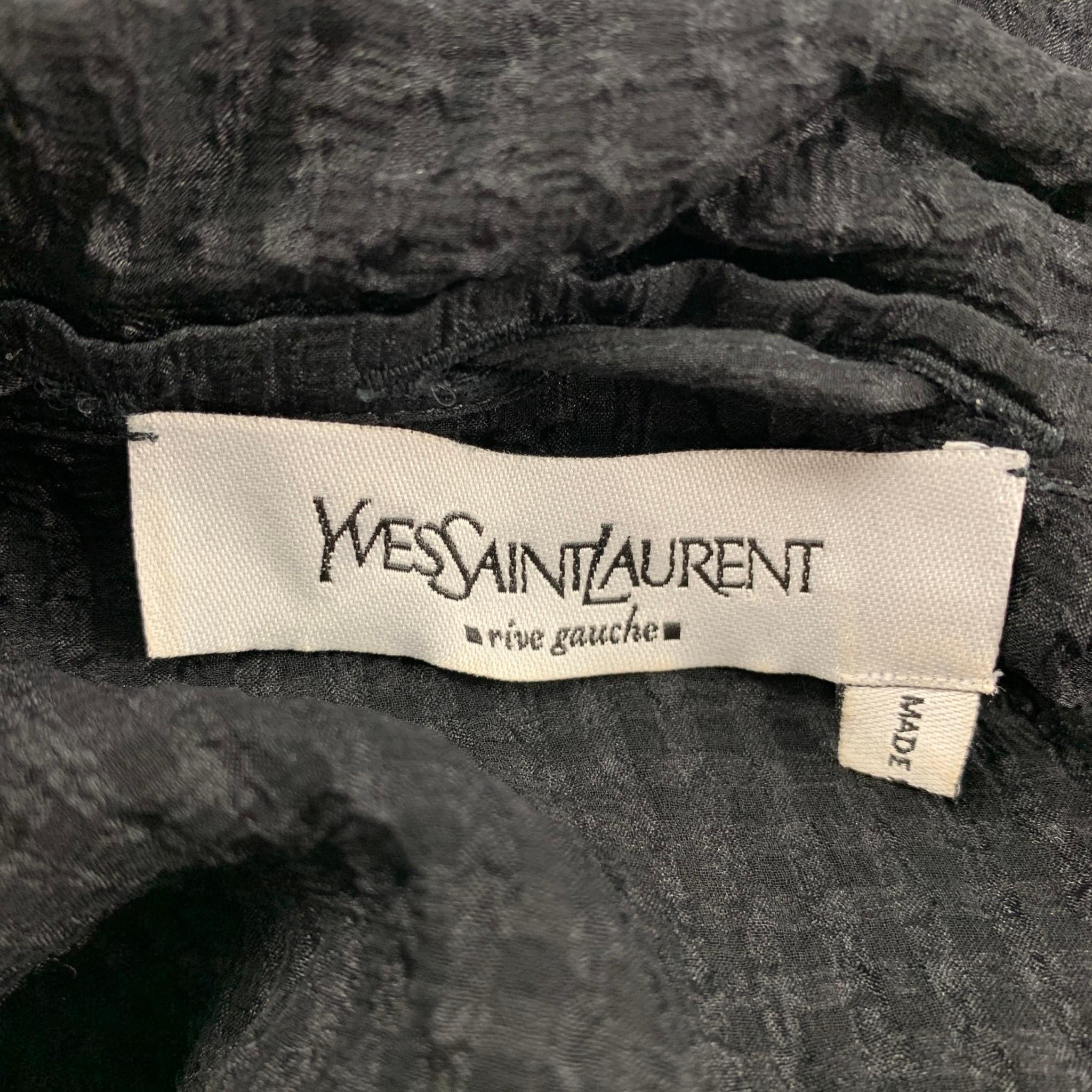 YVES SAINT LAURENT blouse comes in a black see through silk featuring a collar strap detail, patch pockets, dolman sleeves, and a buttoned closure. Made in Italy.

Very Good Pre-Owned Condition. Missing size tag.

Measurements:

Shoulder: 17