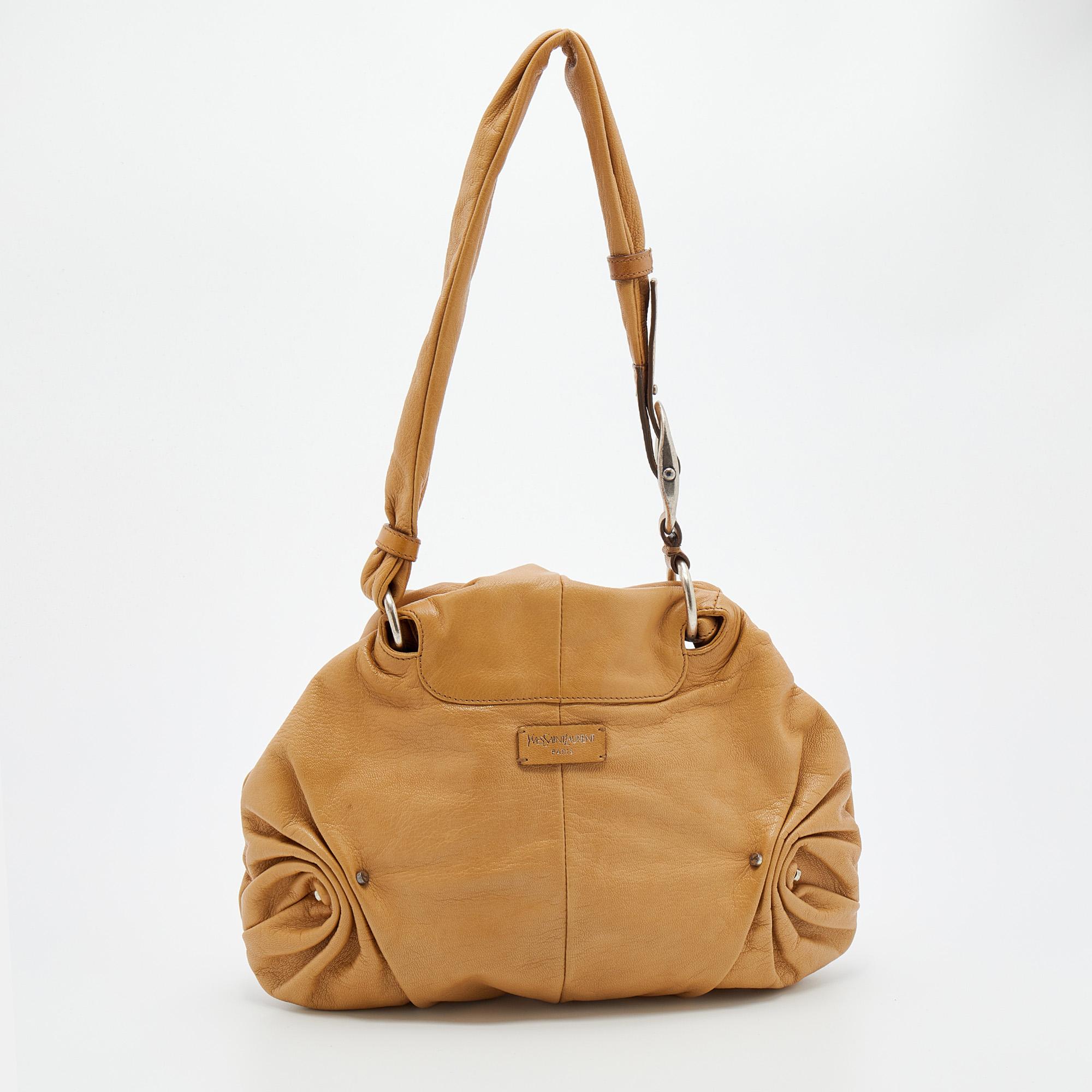 The gathered detailing enhances the silhouette of this Yves Saint Laurent bag. Crafted from tan leather, it is held by a single handle at the top, and its satin interior is spaciously sized.

Includes: Info Booklet