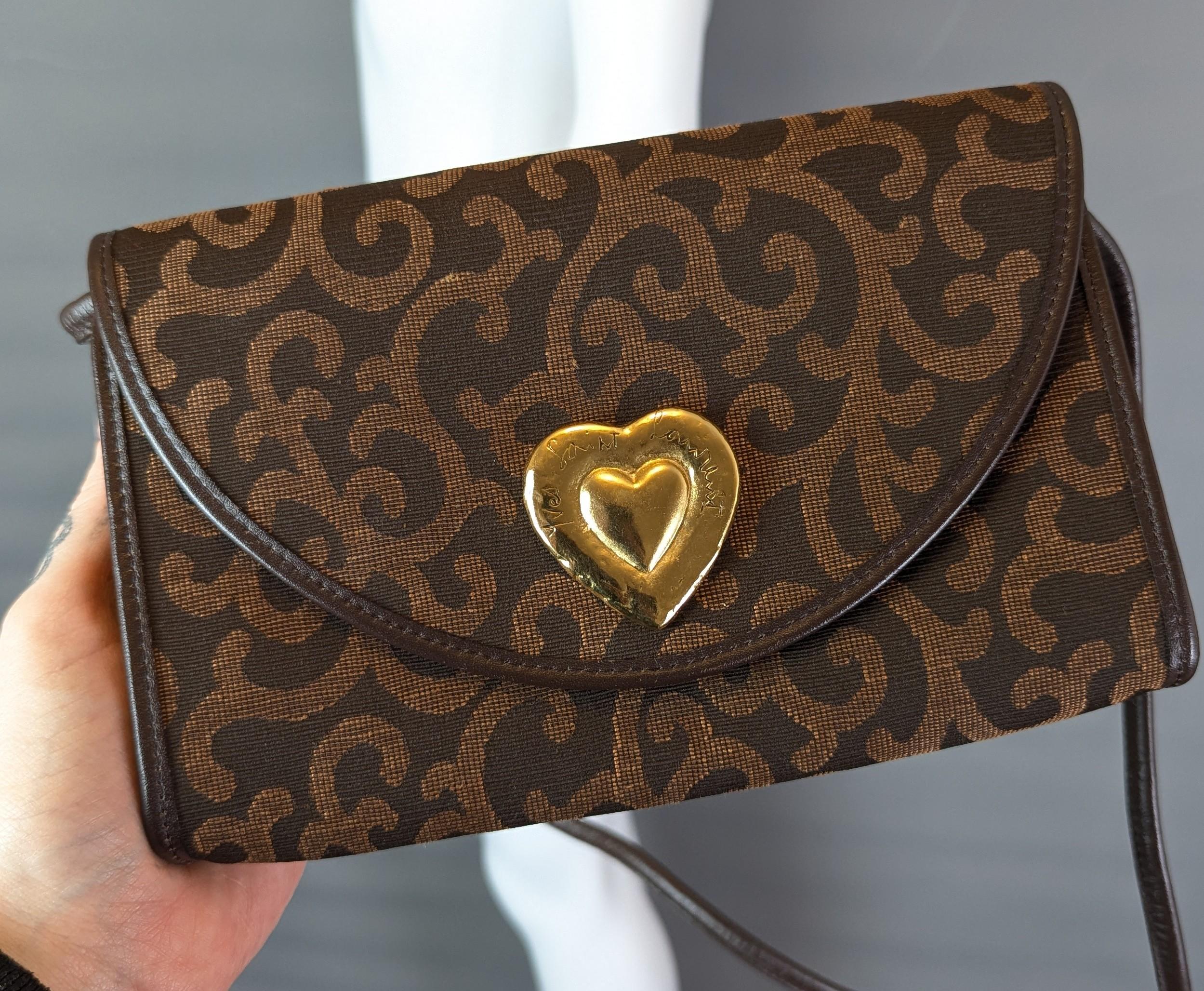Precioso bolso o bandolera vintage YSL de lona marrón.

Tiene suaves tonos marrones cálidos en un lienzo bordado tejido con un estampado abstracto de remolinos, tiene una correa larga para el hombro revestida de cuero marrón y también se puede