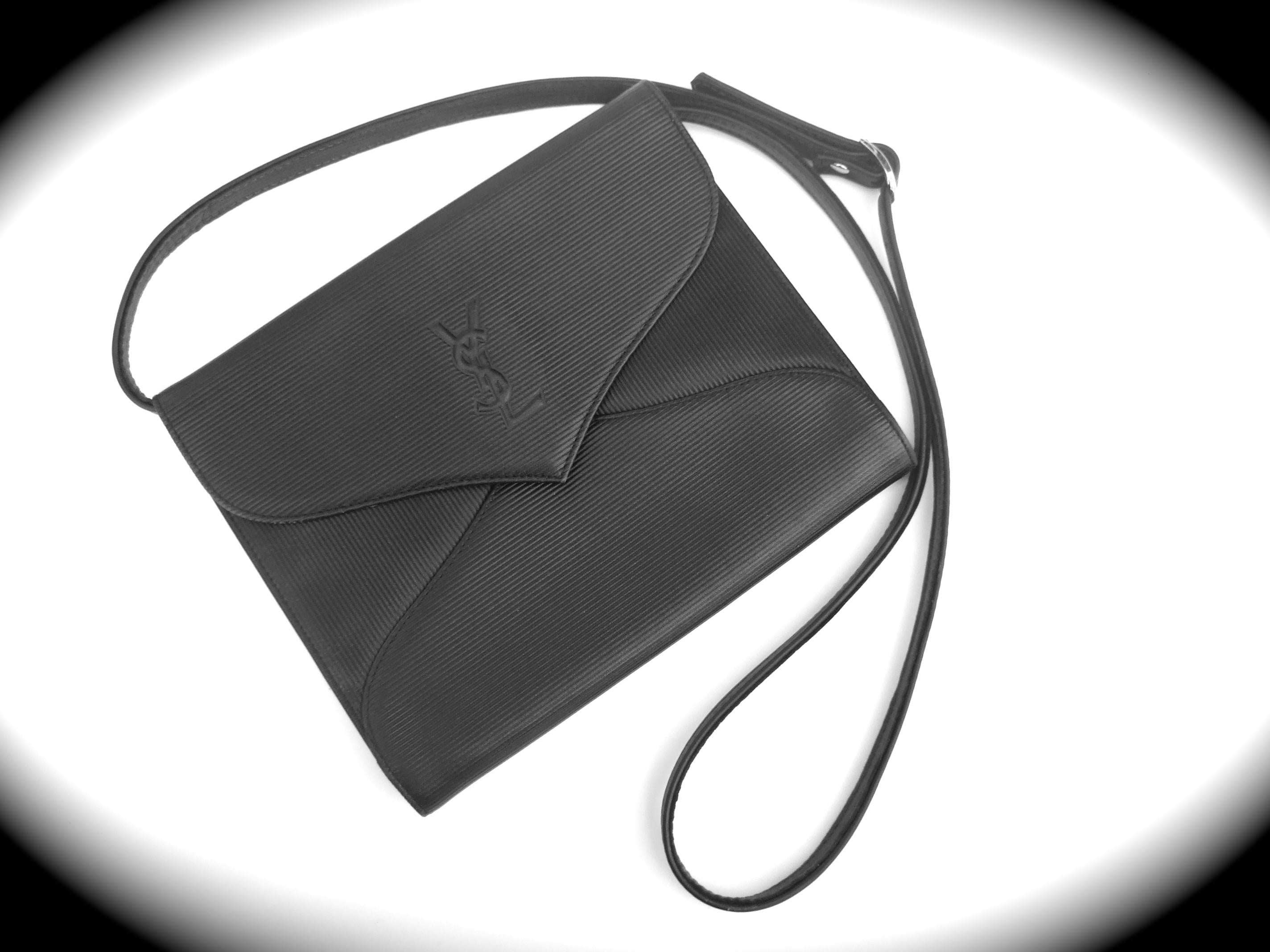 Yves Saint Laurent Chic black leather versatile clutch - shoulder bag c 1980s 
The black leather covering is designed with subtle vertical and horizontal impressed linear bands

The front exterior flap cover is adorned with Saint Laurent's embossed