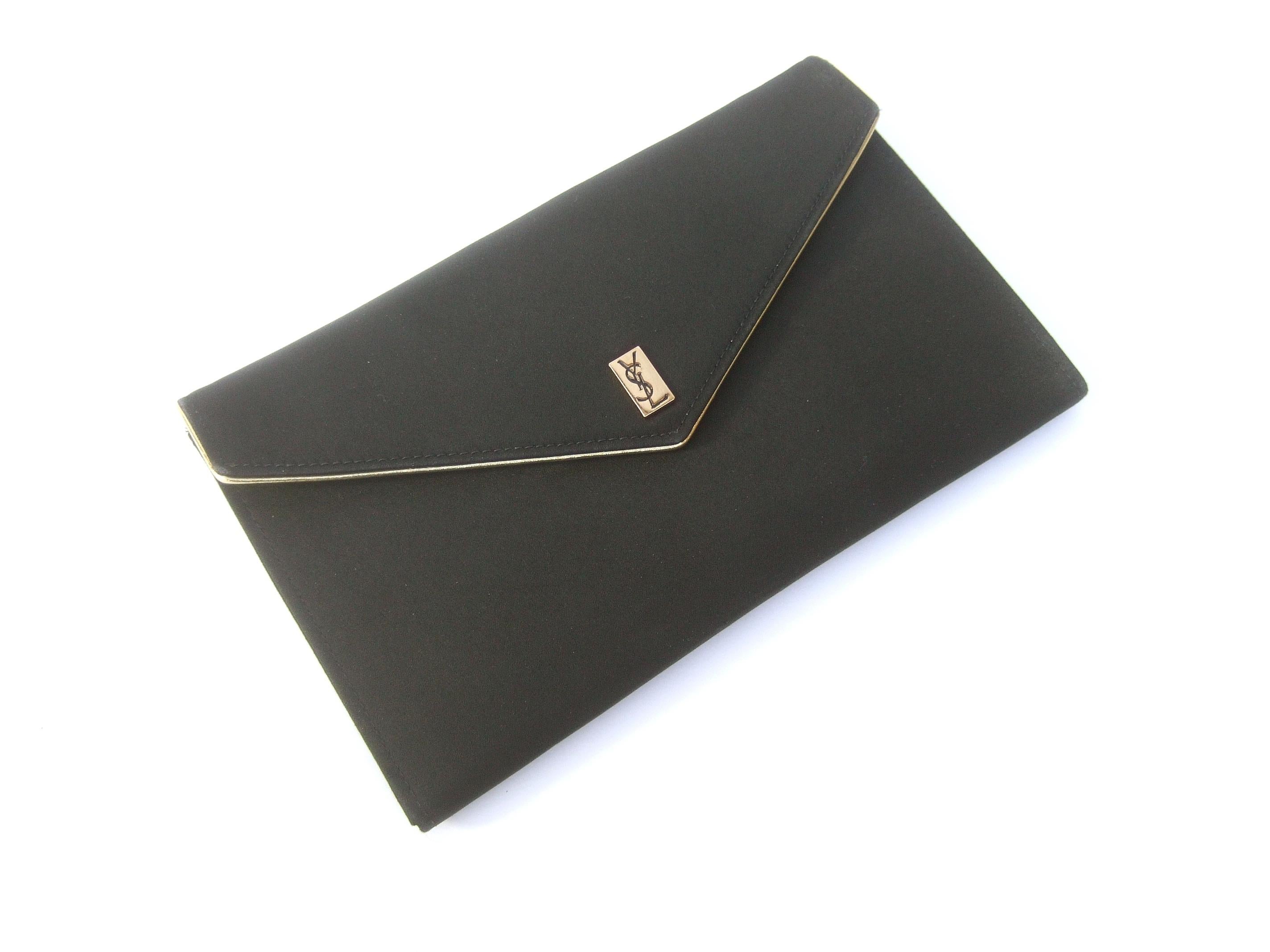 Yves Saint Laurent Black satin clutch bag c 1980s
The elegant clutch is adorned with Saint Laurent's iconic restrained YSL initials on a gilt metal plate on the front flap cover. The flap cover is accented with gold metallic piping trim

The