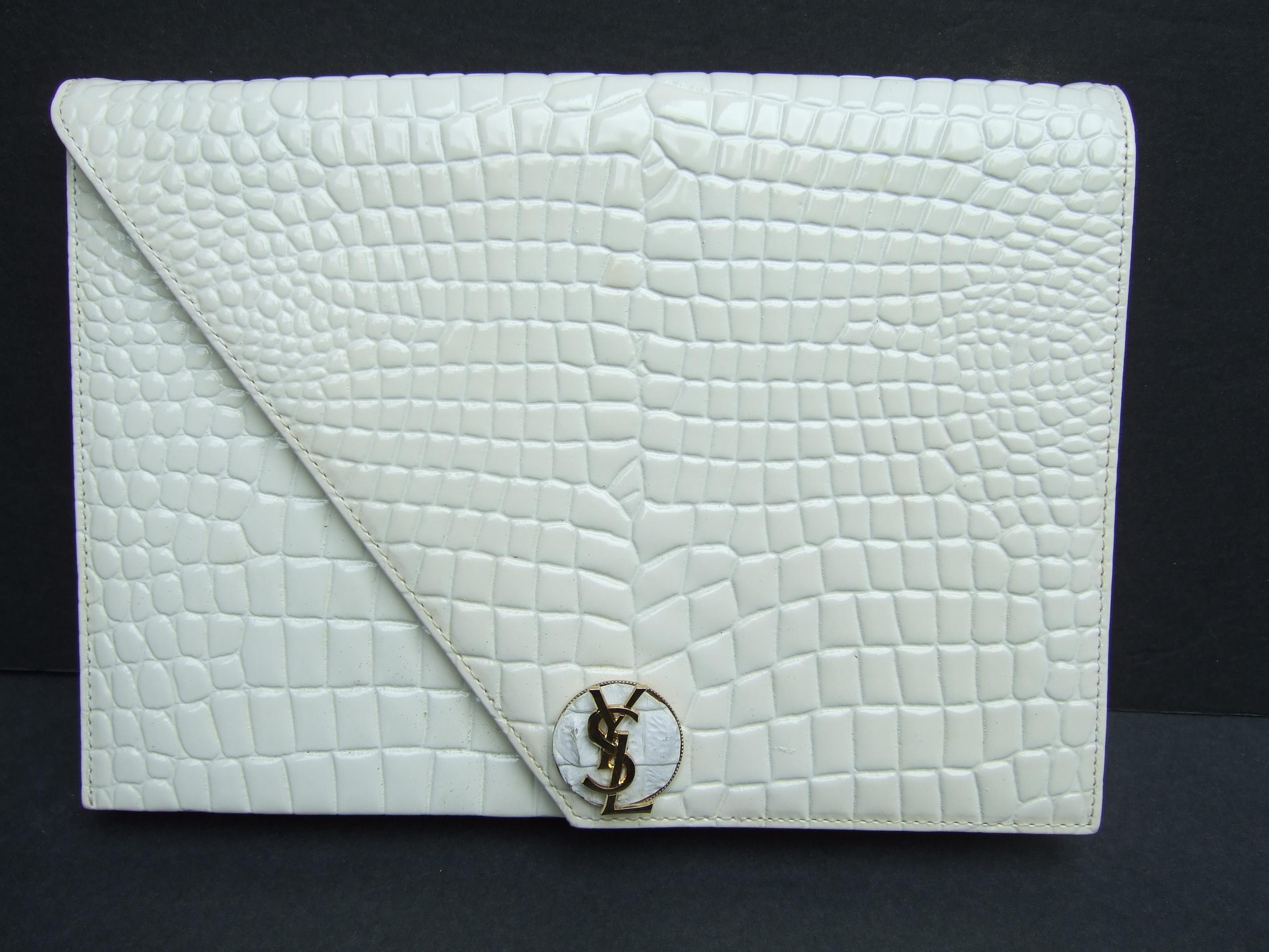 Yves Saint Laurent Chic embossed cream leather clutch c 1980s
The stylish embossed leather clutch is adorned with Saint Laurent's 
iconic gilt metal Y.S.L. initials 

The exterior leather covering has an embossed scale design in a cream color
shade