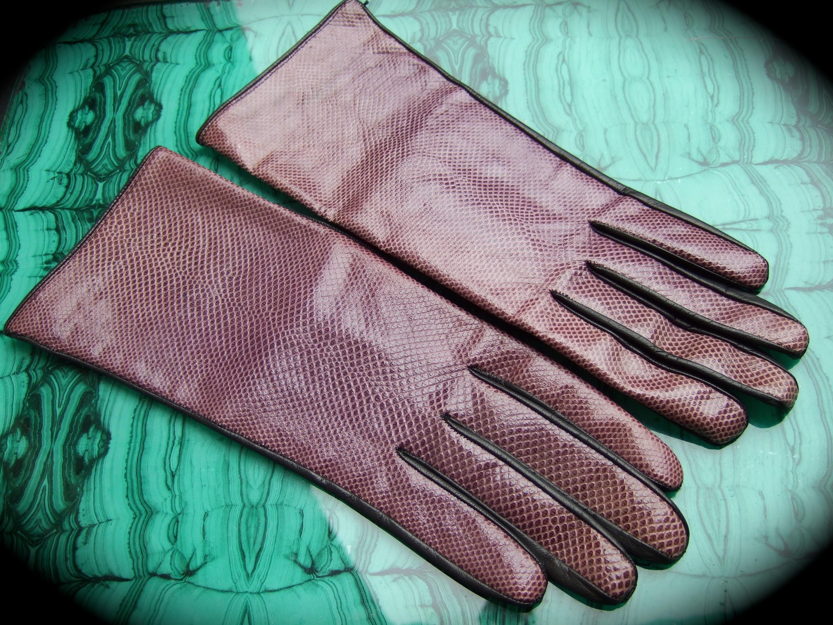 Yves Saint Laurent Chic geprägte lila Lederhandschuhe c 1980s
Die stilvollen Handschuhe sind aus gedämpftem, dunkelviolettem, geprägtem Leder gefertigt, das Reptilienhaut nachempfunden ist

Die äußere Unterseite ist aus schwarzem Glattleder