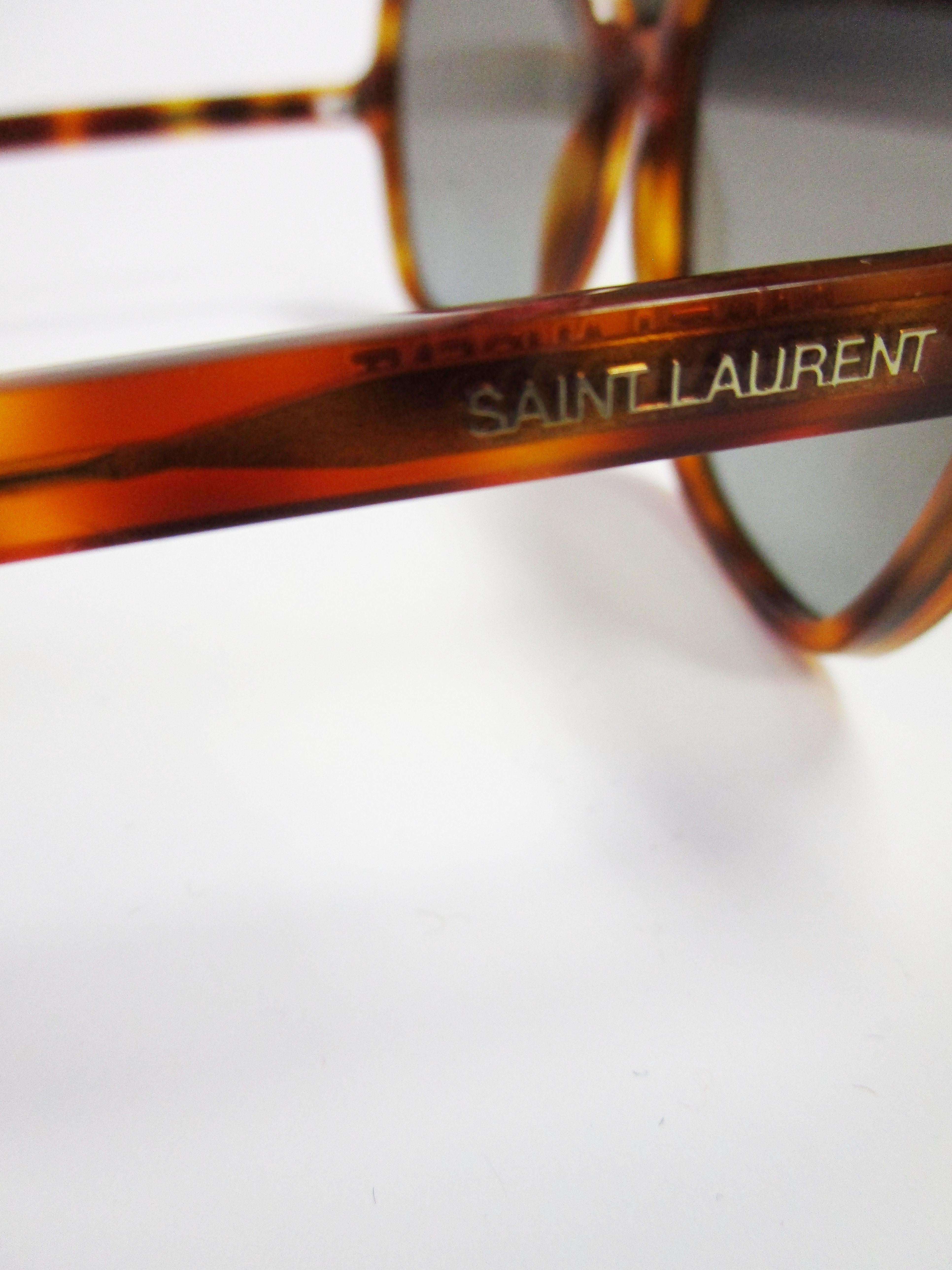 
Take a look at these timeless contemporary sunglasses from Yves Saint Laurent!
They feature a dark tortoise colored frame and tinted grey lenses. 
These shades easily elevate any outfit in your wardrobe whether it be business or casual!

Temple