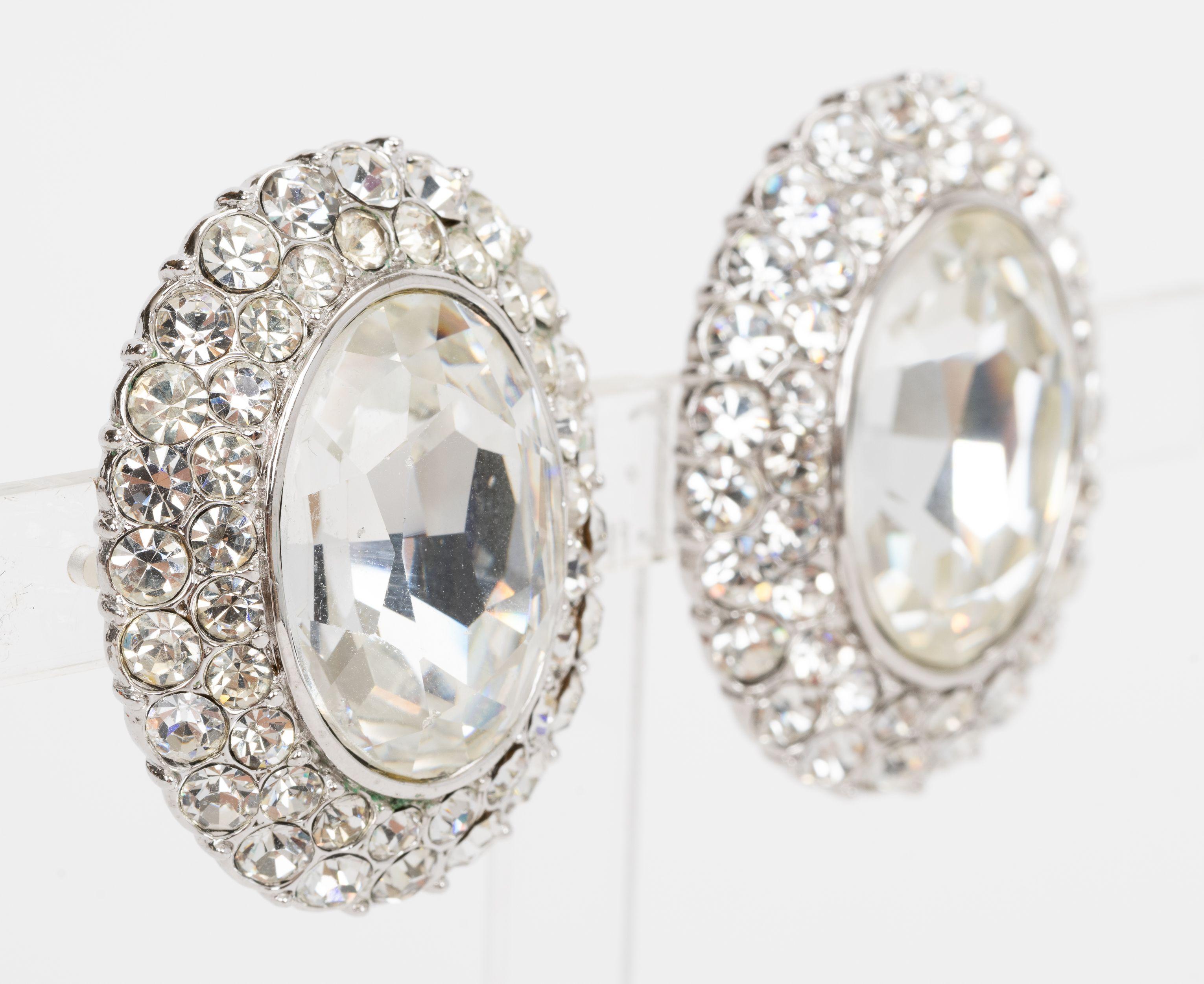 Die Yves Saint Laurent Kristall-Ohrringe haben einen Strassstein in der Mitte und runde Kristalle rundherum. Die Ohrringe lassen sich leicht anstecken. Lieferung mit Samtbeutel.