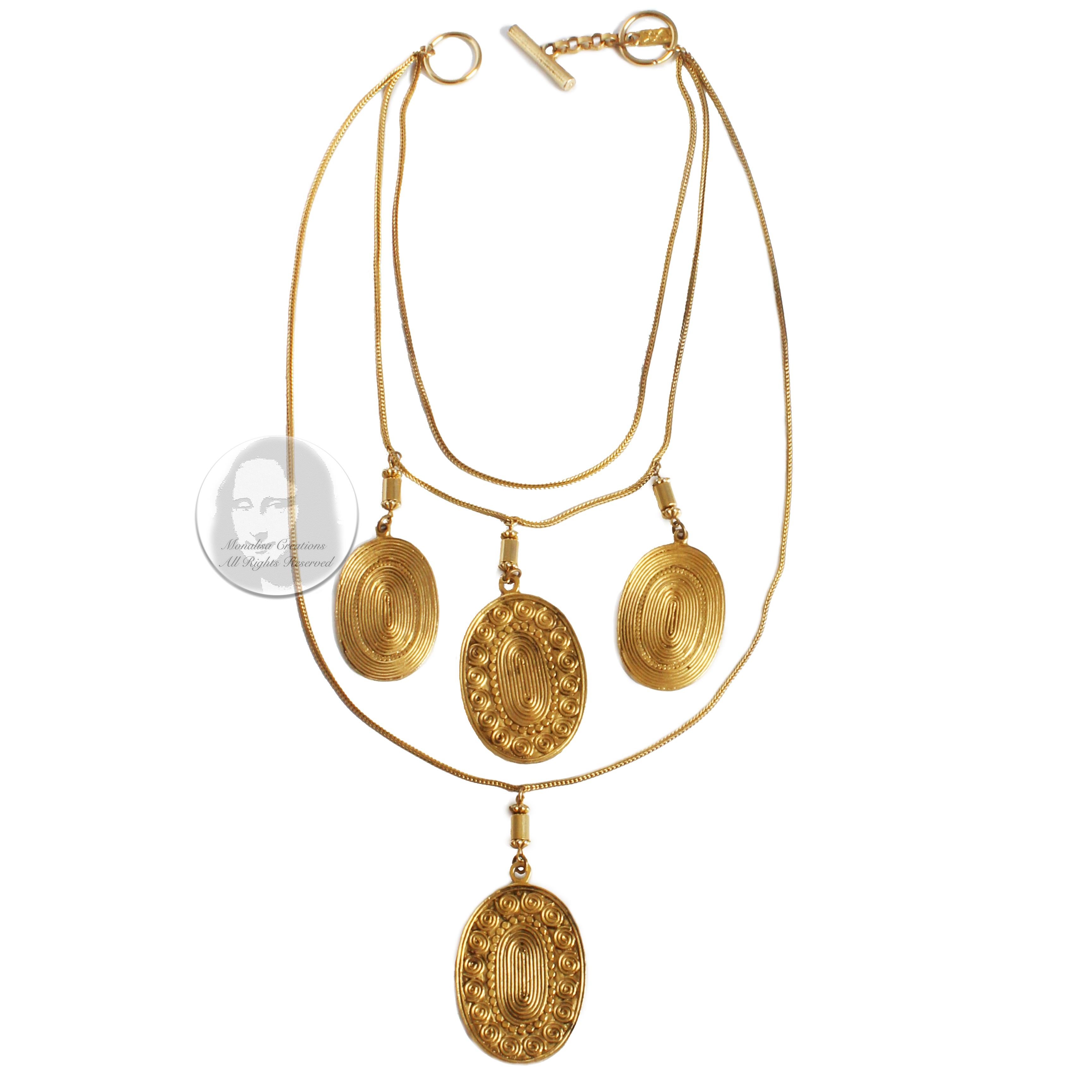 Vintage coin or medallion necklace, made by Yves Saint Laurent, most likely in the late 70s. Made from gold metal, it features three chain strands with a total of four dangling medallions.  Each Etruscan-style medallion features a swirl pattern on