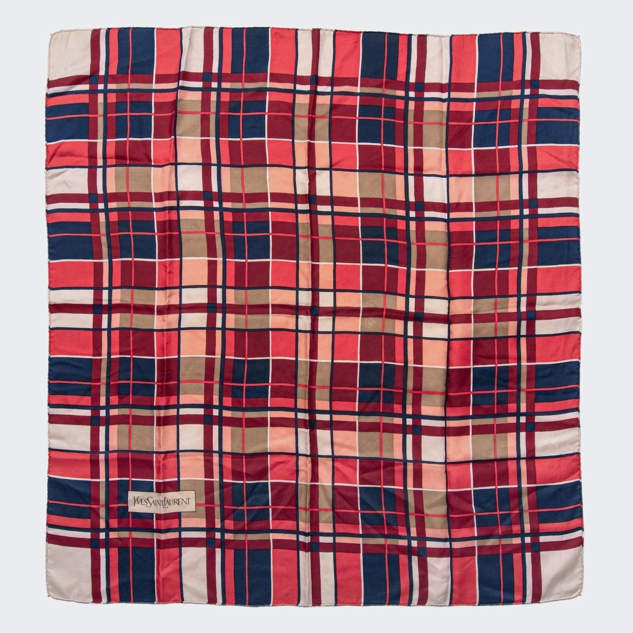 This is a beautiful 1980s Yves Saint Laurent silk scarf. It features one of the plaid prints the brand is renowned for in a wonderful colour combination of coral red, ink blue, maroon and ivory.

The square design is made from a crisp silk twill