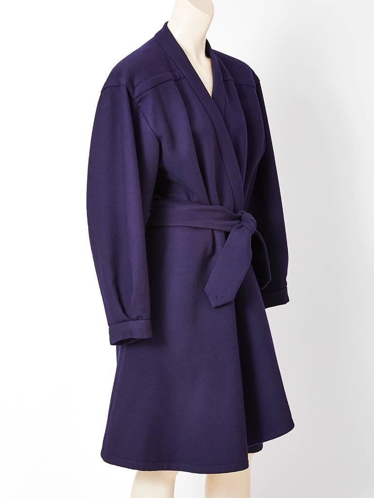 Yves Saint Laurent, couture, navy blue, wool, belted wrap coat having no collar, deep sleeves and asymmetrical hem in the front.
This is a numbered couture piece but made especially for the client out of the collection season.C.1980's.