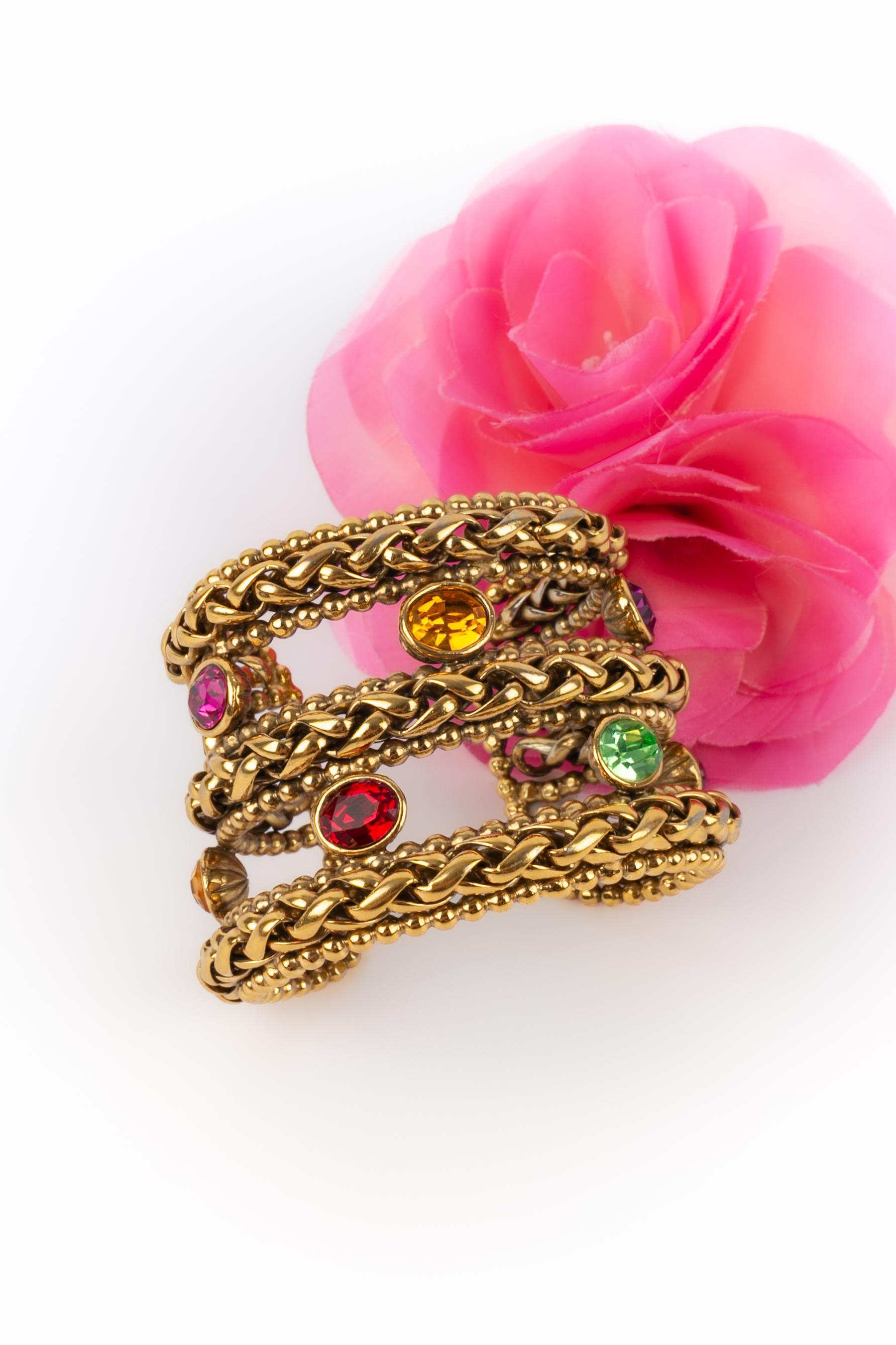 YVES SAINT LAURENT - (Made in France) Goldenes Metallarmband mit mehrfarbigen Strasssteinen verziert.

Bedingung:
Sehr guter Zustand

Abmessungen:
Länge: 14 cm - Öffnung: 2,5 cm

SKU:BRA61