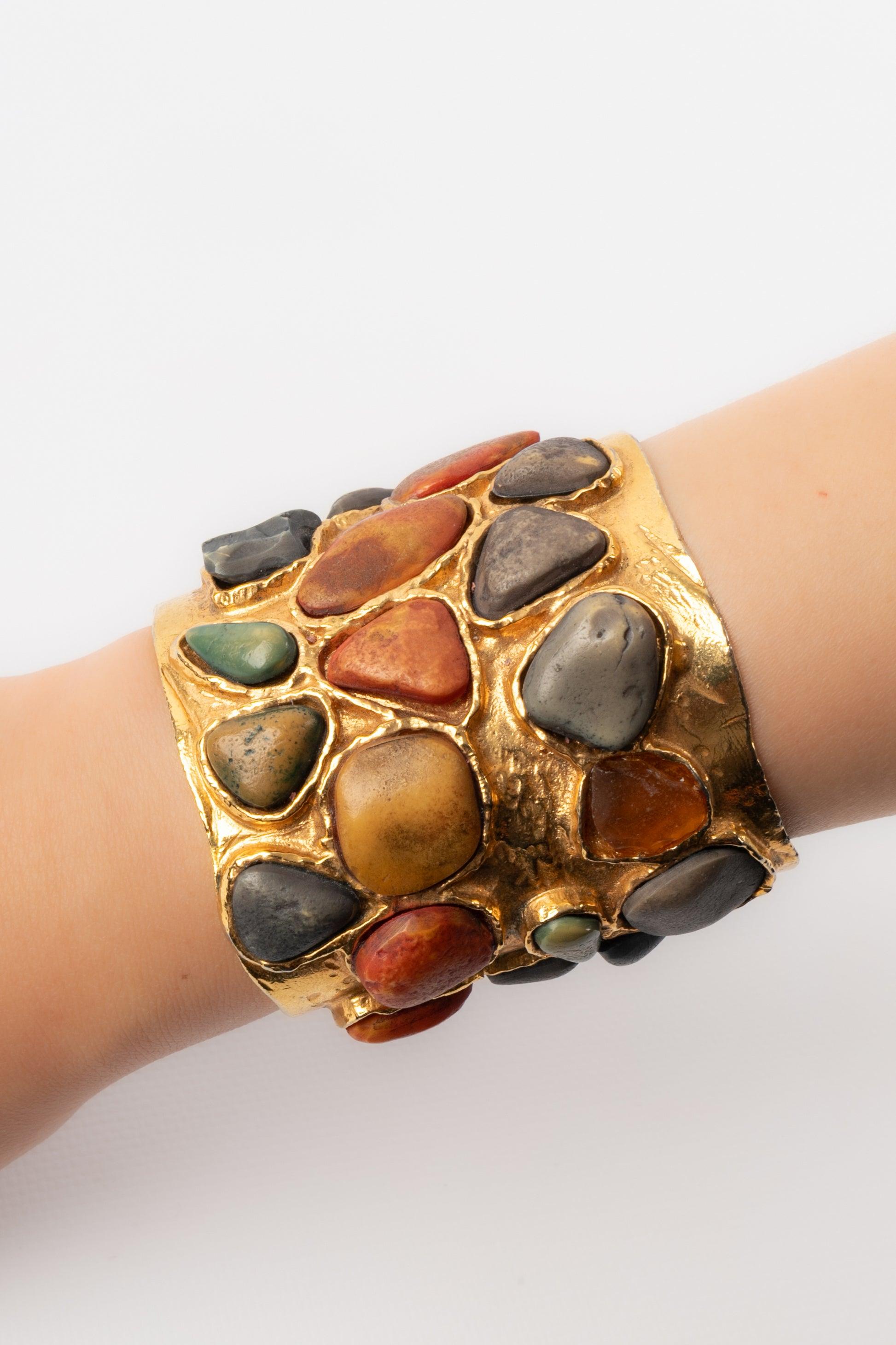 Yves Saint Laurent - (Made in France) Beaten golden metal cuff bracelet ornamented with resin cabochons imitating hard stones.

Additional information: 
Condition: Very good condition
Dimensions: Height: 6.5 cm - Maximum circumference: 16 cm

Seller