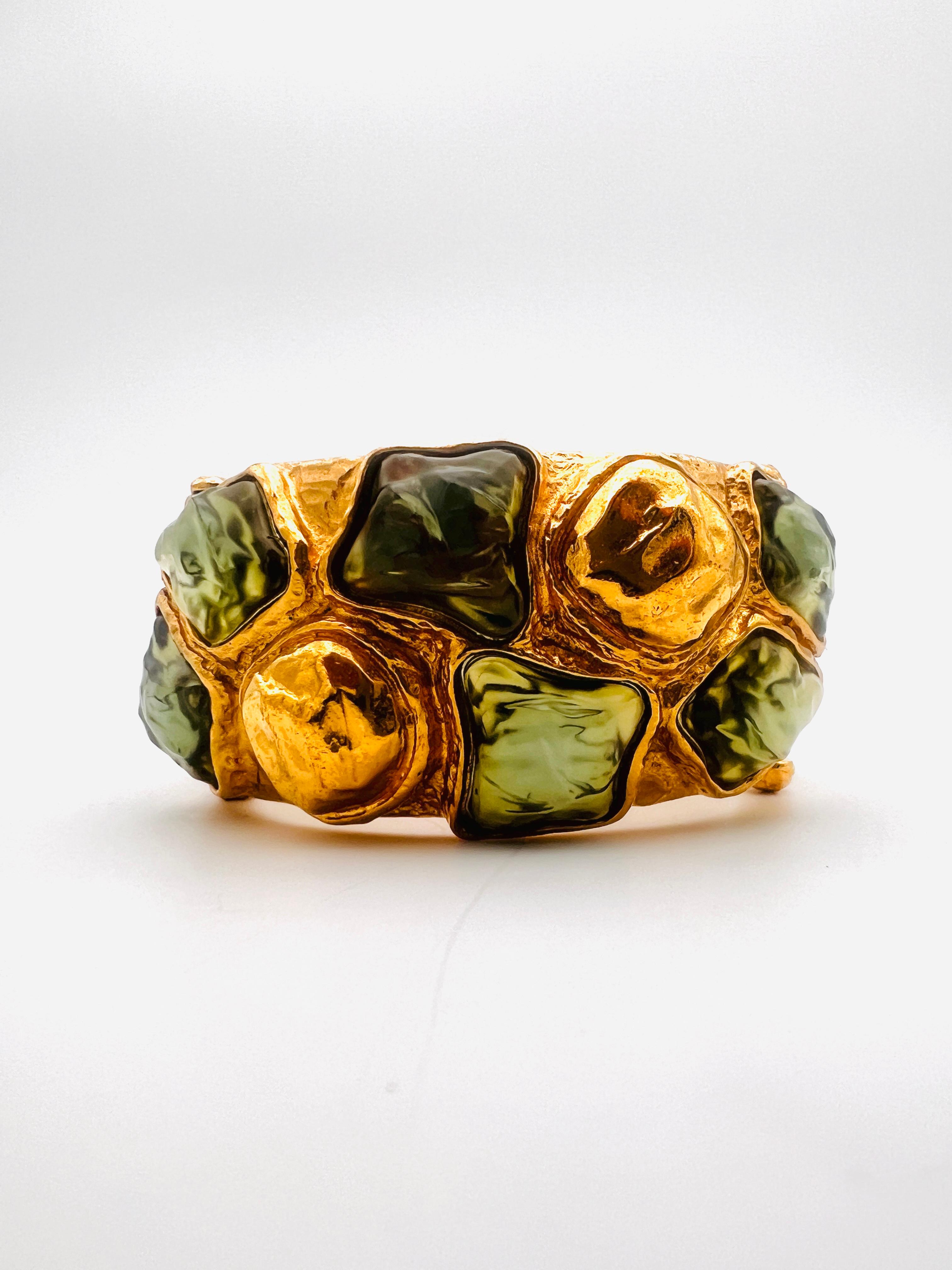 Superbe manchette massive d'Yves Saint Laurent en métal doré avec cabochon verdâtre. Extrêmement rare !
Signé à l'intérieur de YSL. Fabriqué en France .