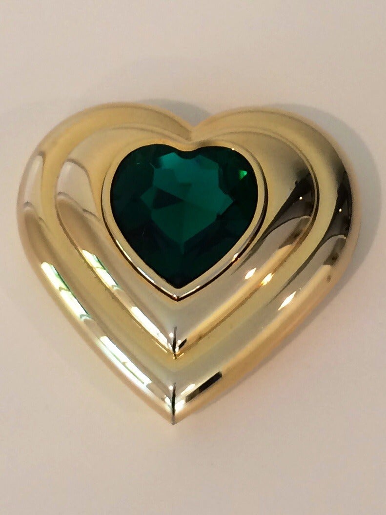 A Beautiful and unused Yves Saint Laurent heart-shaped compact with emerald green crystal rhinestones on the lid of the compact. 
Mirror inside
Made in France. Gold plated
From the 1980's
Measurements are 2-3/4