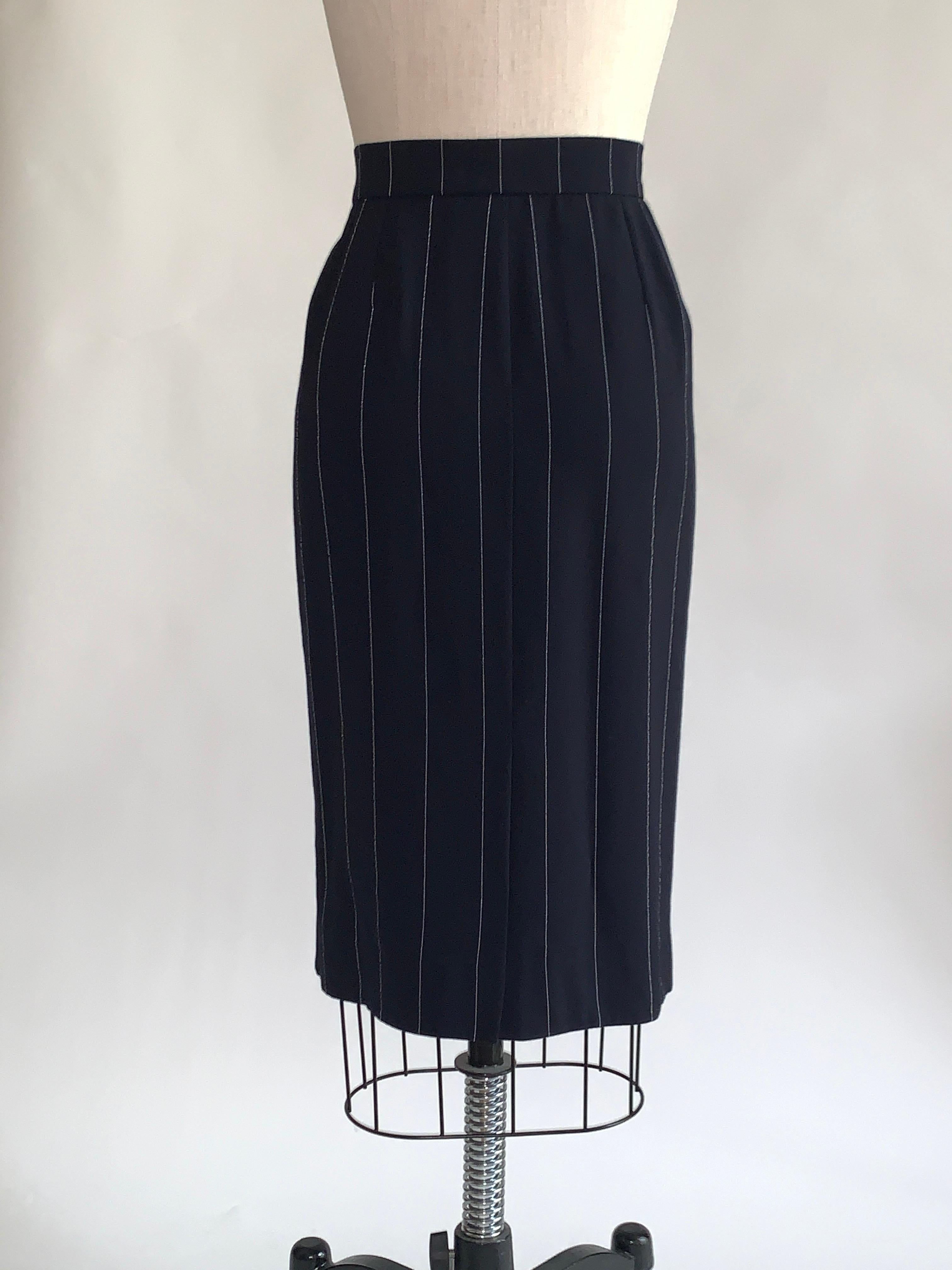 1990s vintage Encore by Yves Saint Laurent pencil skirt in navy blue with skinny white pinstripe throughout.  Side zip and button closure. Short slit at center back.

60% wool, 39% rayon, 1% polyester. 
Fully lined in 55% acetate, 45% cuprous.

Made