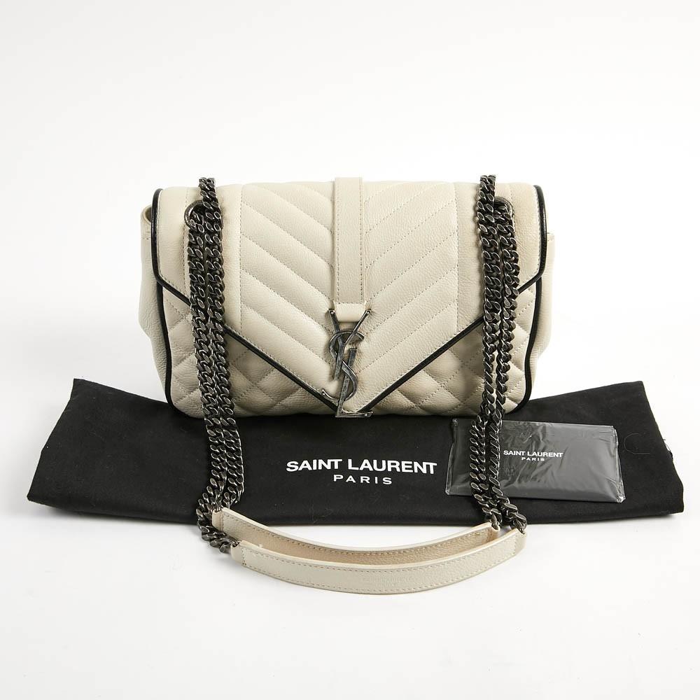 Lovely and practical envelope YSL bag in beige leather. Closes with a magnetic snap closure. Inside lining in black fabric, with a small flat  leather pocket (credit card size). The strip  (120 cm), made of metal and leather, can be worn doubled on