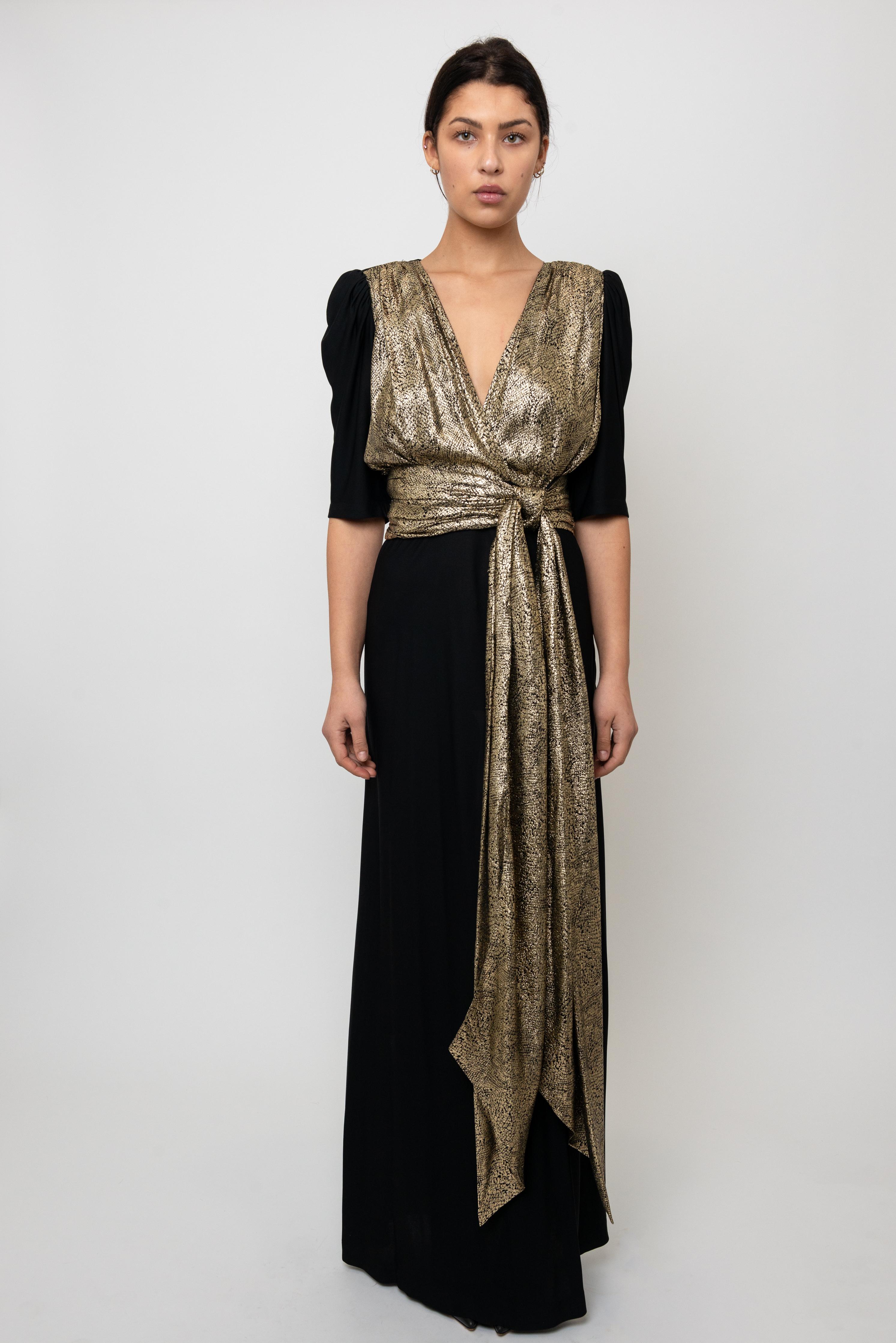 Dieses atemberaubende Kleid von Yves Saint Laurent aus der kultigen Herbst/Winter 1986 Laufstegkollektion ist ein echter Hingucker. In luxuriösem Schwarz mit auffälligen goldenen Akzenten verkörpert dieses Stück die charakteristische Raffinesse und