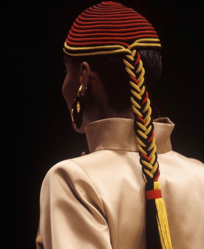 Yves Saint Laurent - Hut für die Modenschau in Rot, Schwarz und Gold, mit einem Zopf, der mit einer Bommel endet.
nicht unterzeichnet.

Zusätzliche Informationen: 
Abmessungen: Umfang: 48 cm, Höhe: 14 cm, Länge Zopf: 42 cm
Zustand: Sehr guter