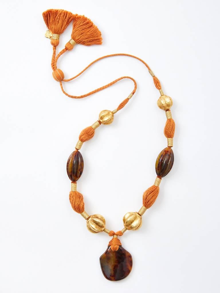 Yves Saint Laurent, RIve Gauche, faux tortoise pendent, having carved gold beads and carved faux tortoise beads on terra cotta toned fine twisted cord. Tassels are at the back with an adjustable slide closure.