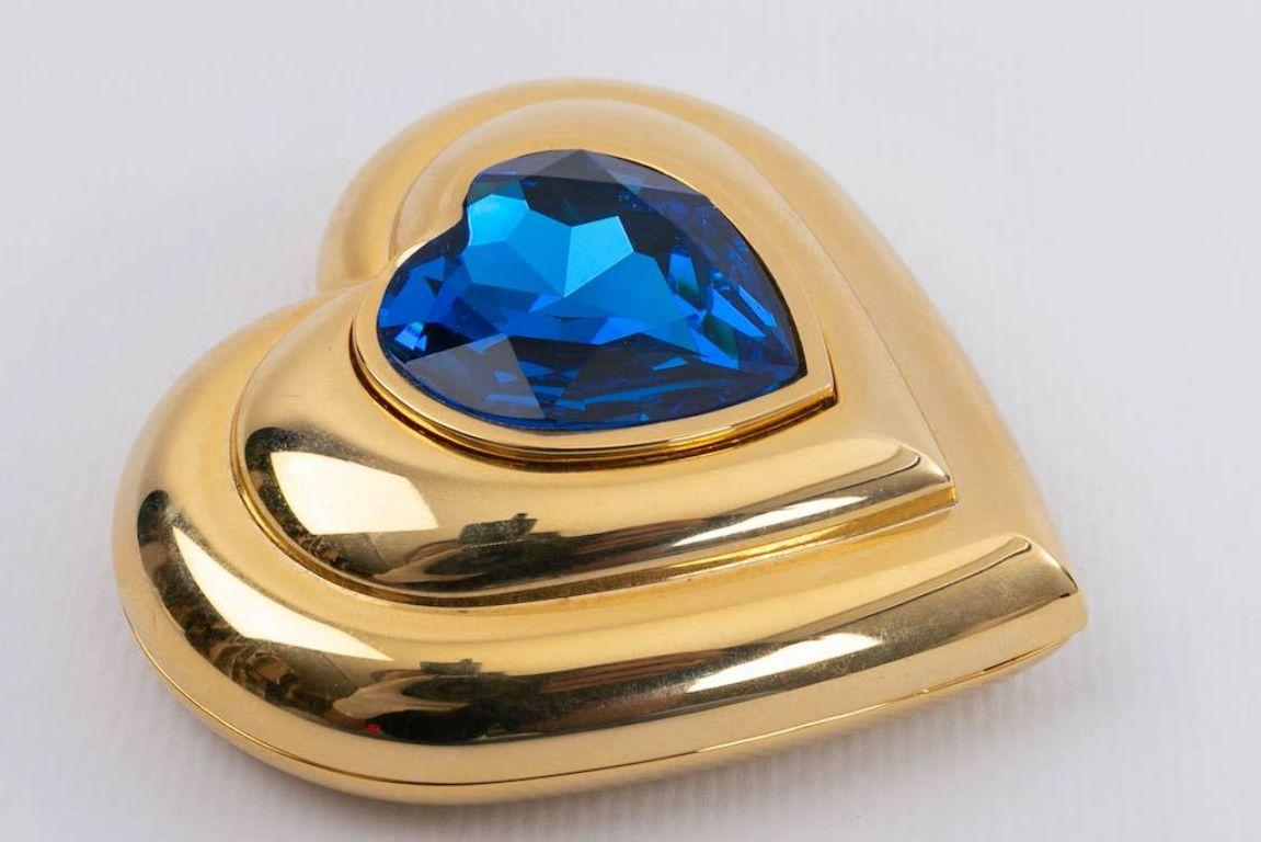 Yves Saint Laurent - Gilded metal compact in the shape of a heart, decorated with a blue rhinestone. 

Additional information: 
Dimensions: 6 cm x 6 cm (2.36