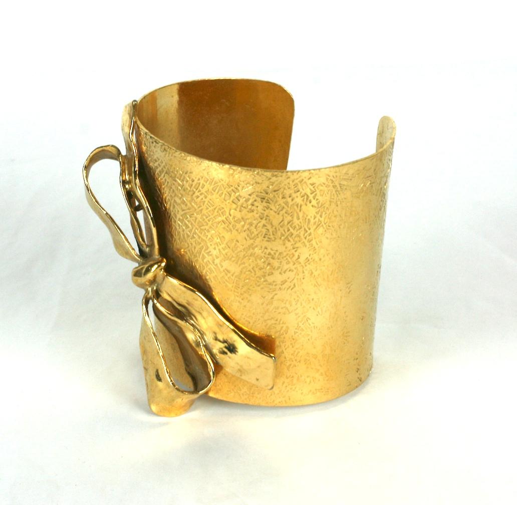Yves Saint Laurent tapered rich gilt textured cuff bracelet. Appliqued with a three dimensional sculpted bow. 
Maison Robert Goossens for Yves Saint Laurent Rive Gauche.
Excellent Condition. 1990's France. 
Signed Rive Gauche
Height 2 5/8