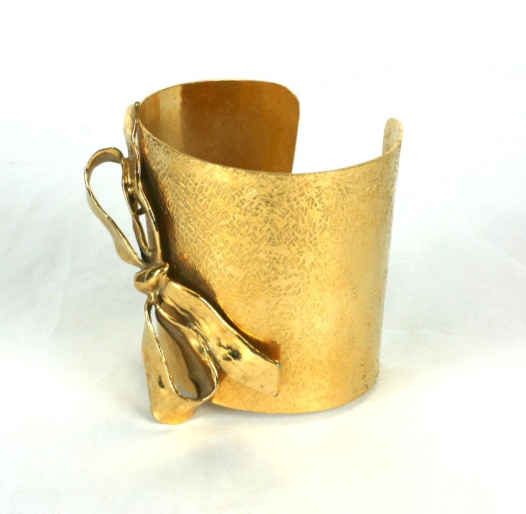Bracelet manchette Yves Saint Laurent effilé et richement texturé en doré. Appliqué d'un nœud sculpté en trois dimensions. 
Maison Robert Goossens pour Yves Saint Laurent Rive Gauche.
Excellent état. france des années 1990. 
Signé Rive