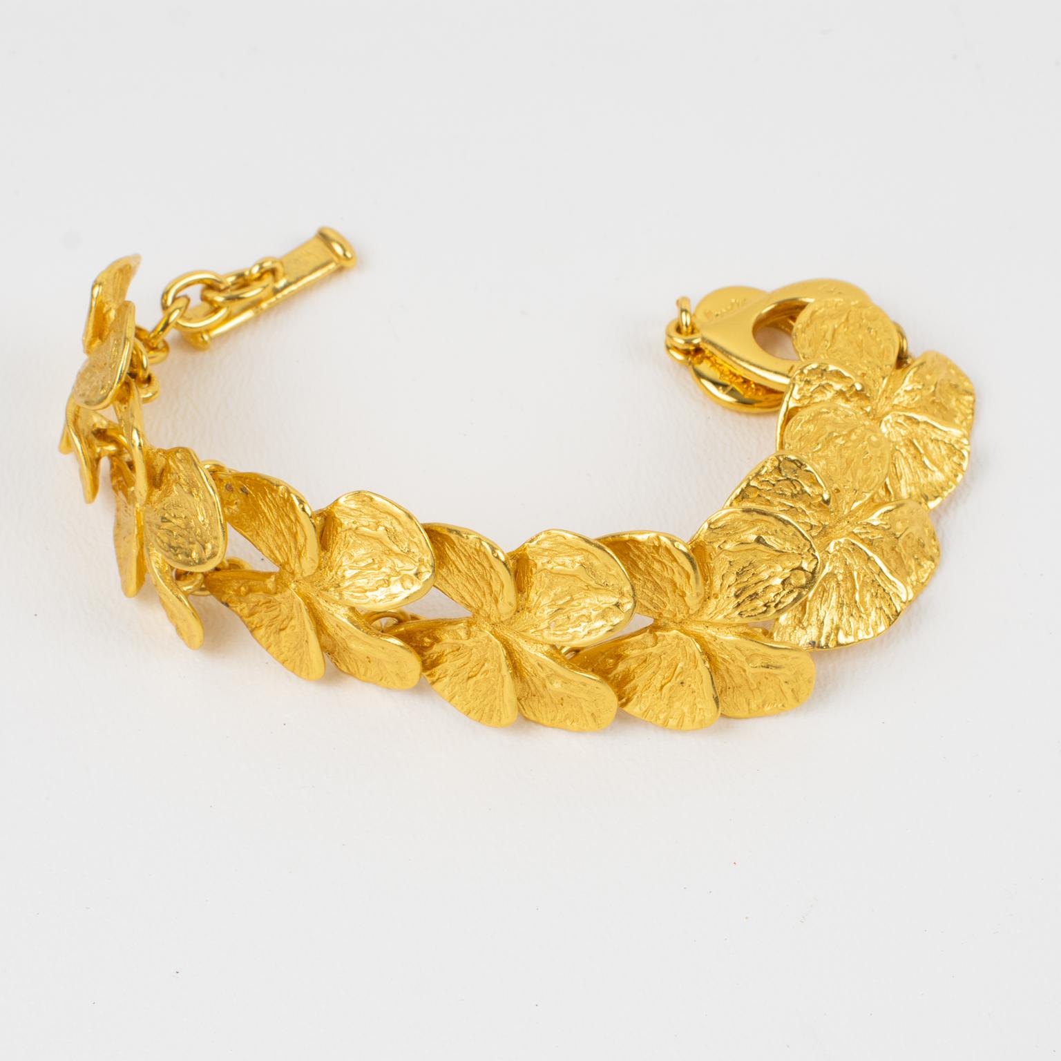 Ce joli bracelet à maillons Yves Saint Laurent YSL Paris présente une forme papillon en métal doré, tout en texture. Le fermoir à bascule est doté de deux plaques en métal doré en forme de cœur portant le logo de la marque. Le bracelet est également