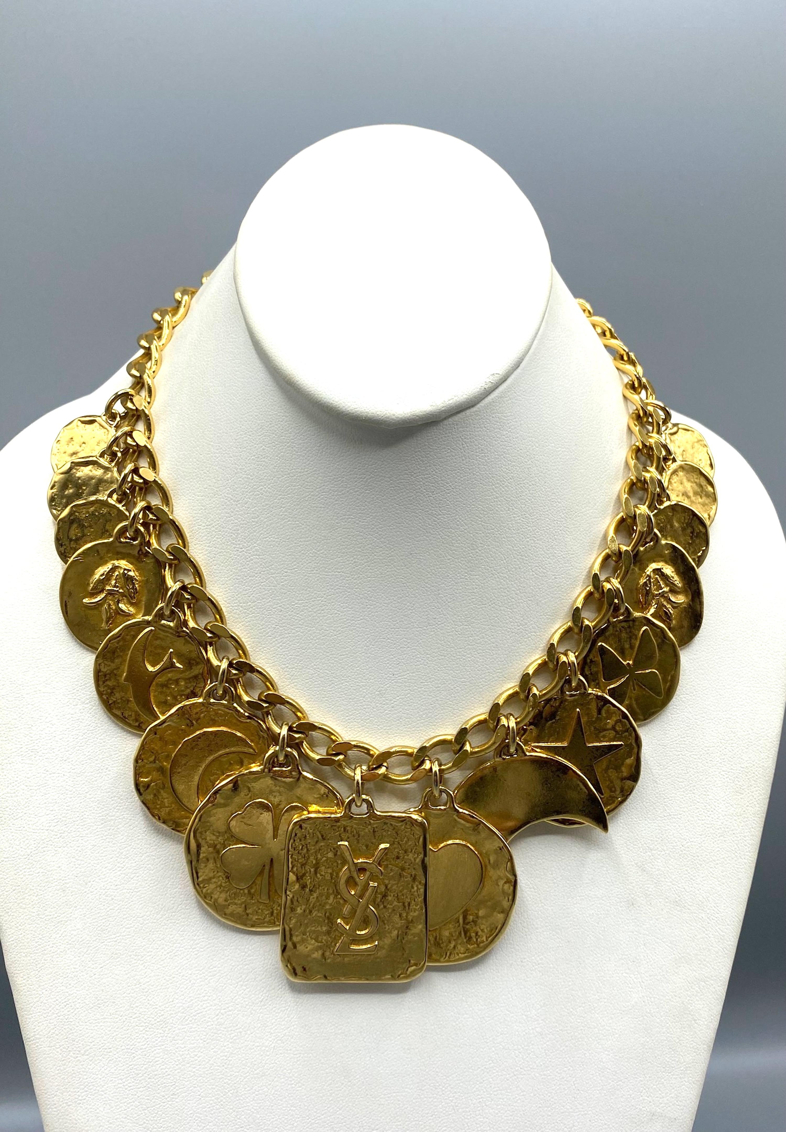 A wonderful 1980s Yves Saint Laurent gold set consisting of a chain necklace with 15 large charms with various design and a chain bracelet with 8 matching charms. The center charm has the YSL logo on the necklace. The other charms feature a single