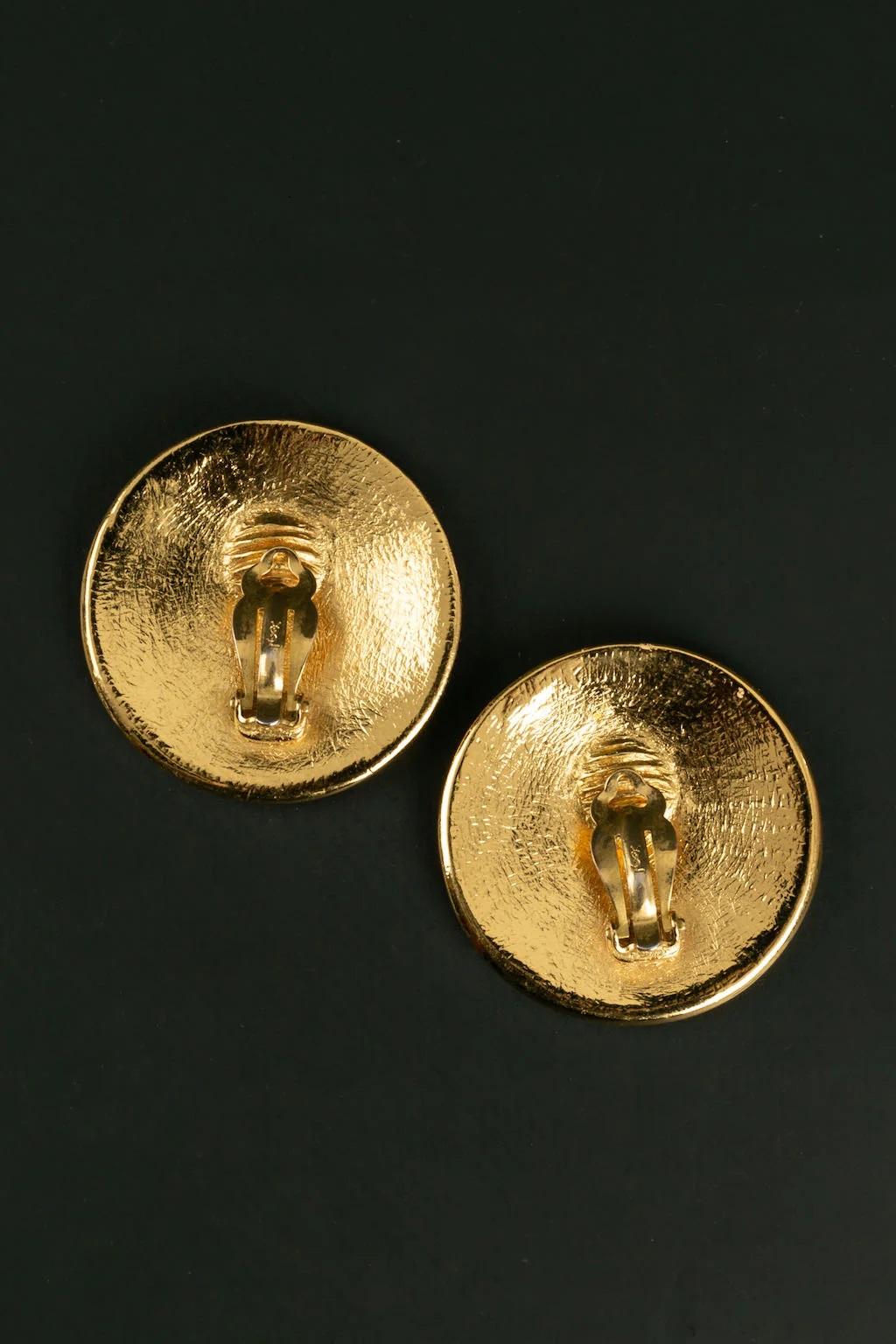 Yves Saint Laurent -Golden metal clip earrings featuring a shield.

Additional information:
Dimensions: Ø 4.3 cm

Condition: 
Very good condition

Seller Ref number: BO257