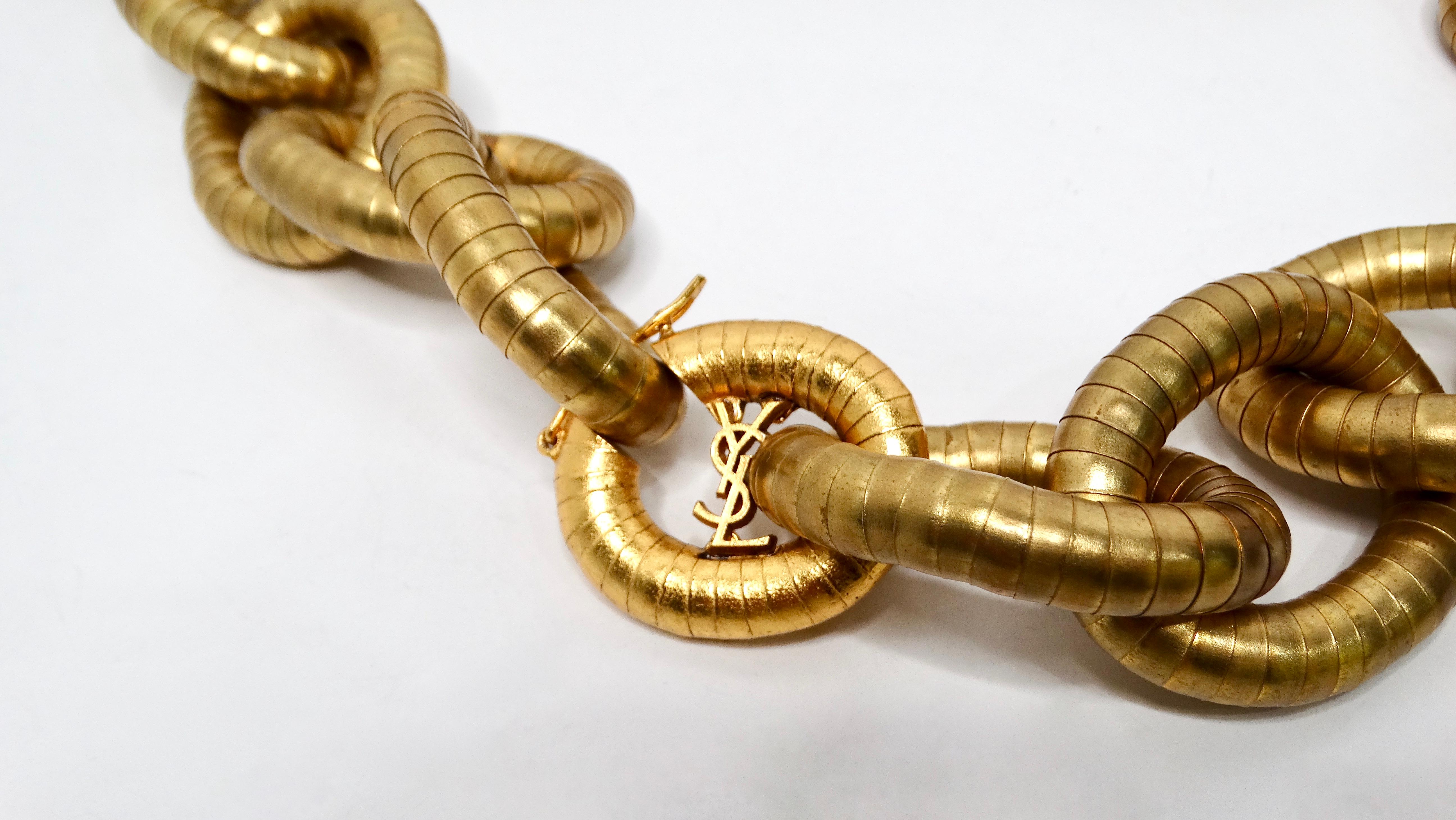 La collana a catena Yves Saint Laurent Serpentine Chunky in oro è un pezzo forte che incarna il lusso e il design audace. Realizzata con dettagli meticolosi, la collana presenta una sostanziosa catena a serpentina, in cui ogni anello brilla di una