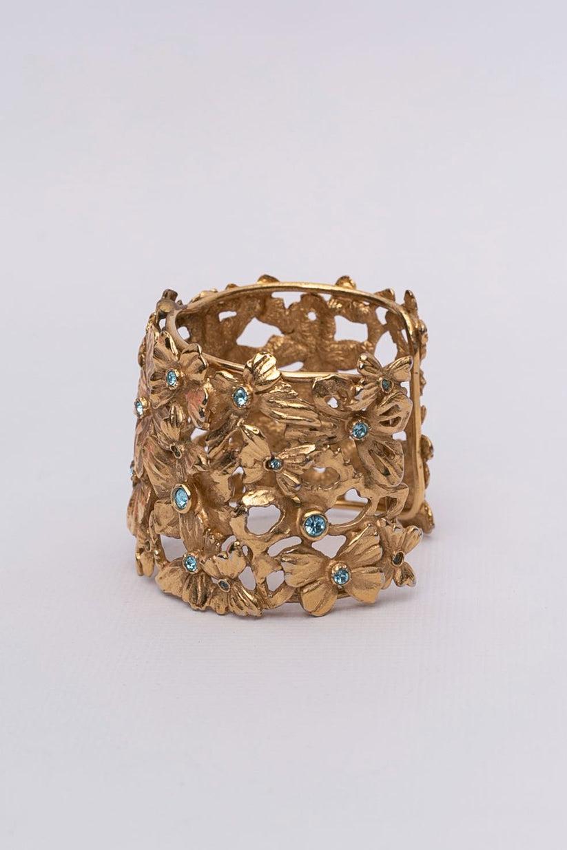 Yves Saint Laurent (Made in France) Openworked gilted metal cuff bracelet adorned with blue rhinestones.

Additional information:

Dimensions: 
Circumference: 14 cm (5.51 in) 
Height: 4.5 cm (1.77 in) 
Opening: 3 cm (1.18 in)

Condition: Very good