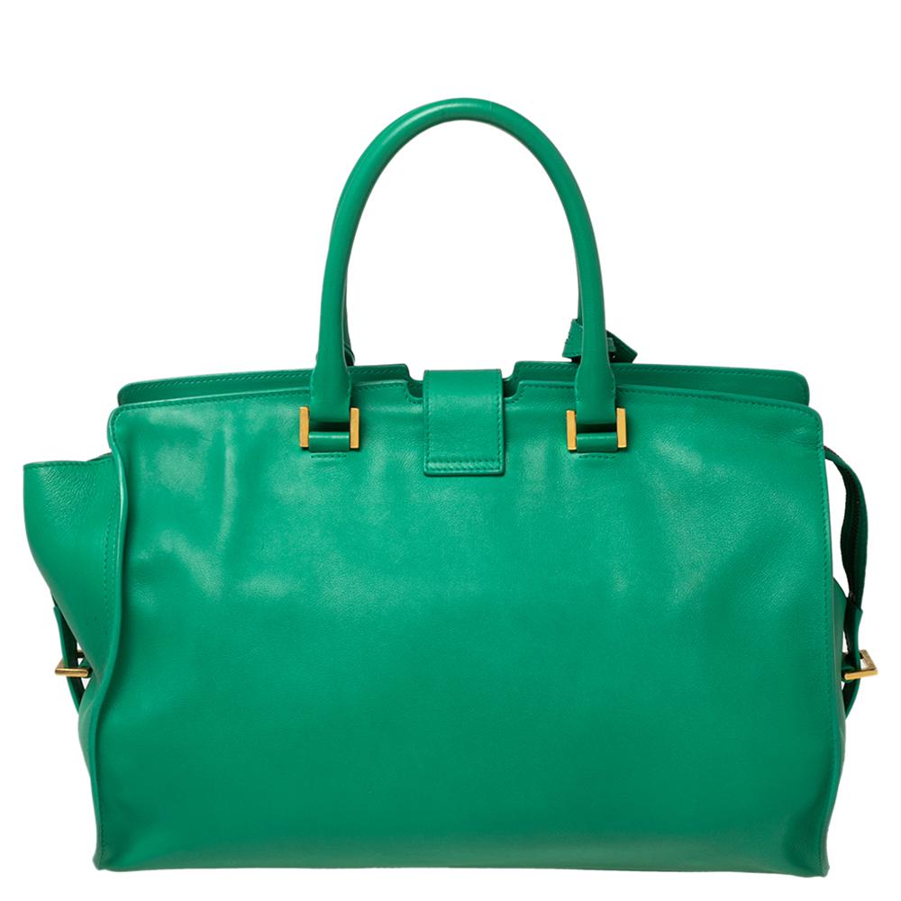 This elegant green Cabas Chyc tote from Yves Saint Laurent is ideal for everyday use. Crafted from leather, the bag is detailed with a gold-tone Y motif snap closure and dual-rolled handles. The top zip closure opens to a spacious interior that is