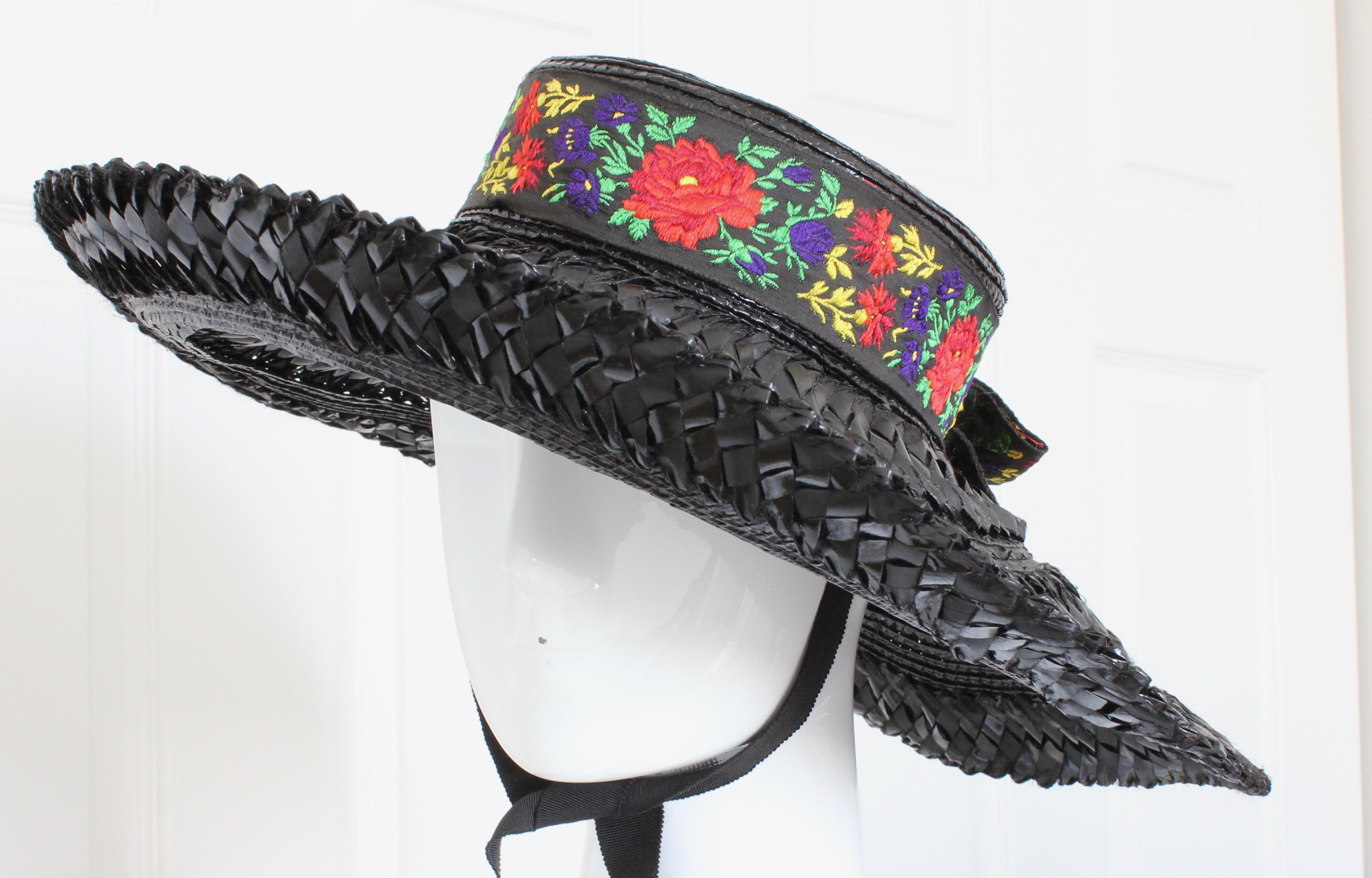 This fabulous black straw hat was made by Yves Saint Laurent Rive Gauche, most likely in the 1970s.  It features a wide floppy brim, brilliant colored florals trimming the crown and as a bow in back, and long grosgrain ties attached to the interior.