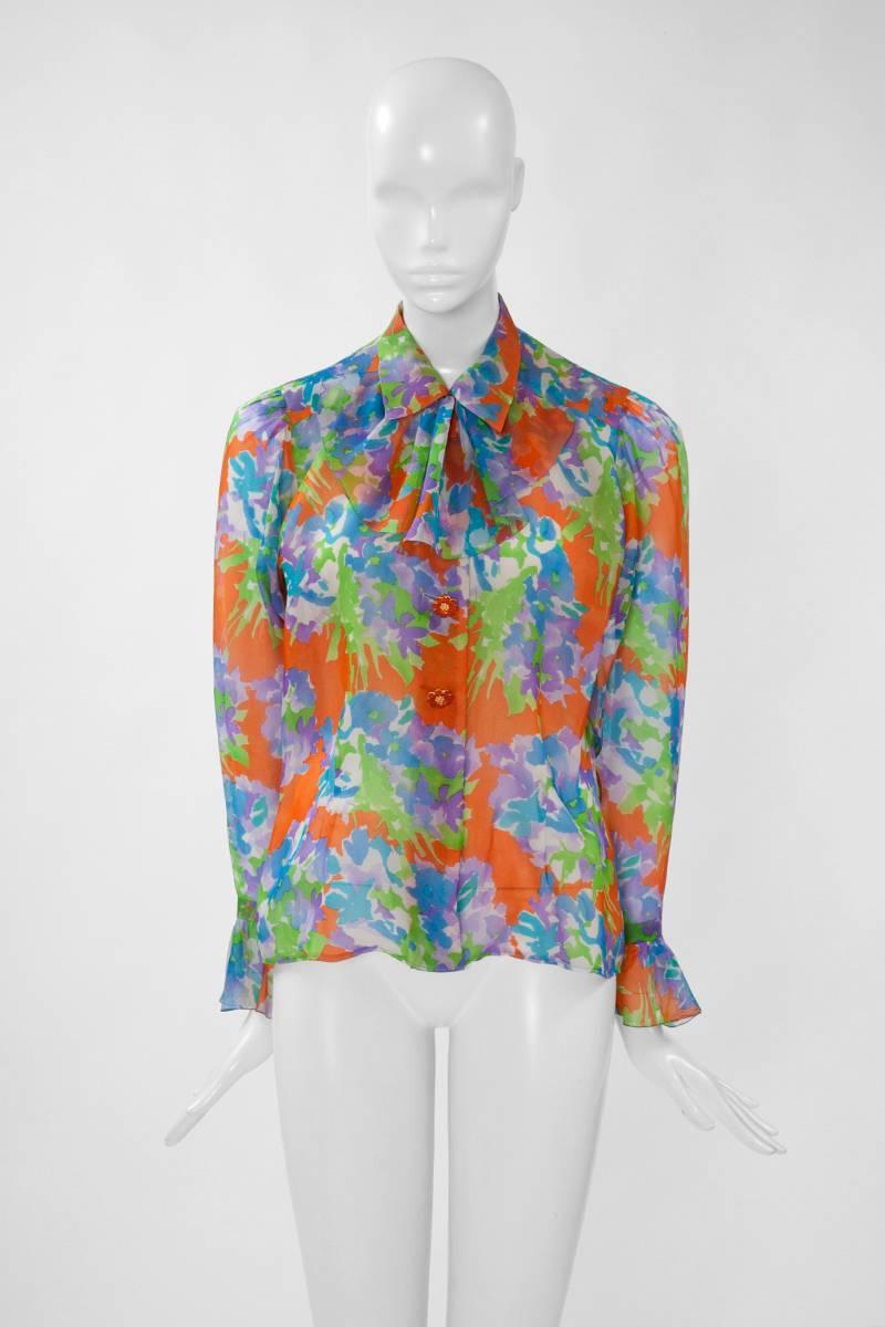 Diese leuchtende, mit Blumen bedruckte Bluse aus der YSL-Frühjahrs-Sommer-Haute-Couture-Kollektion 1993 ist eine echte Ode an den Frühling. Dieses Kleidungsstück aus Organdy-Seide ist mit einem abnehmbaren Jabot (siehe Abbildung 10) versehen, das