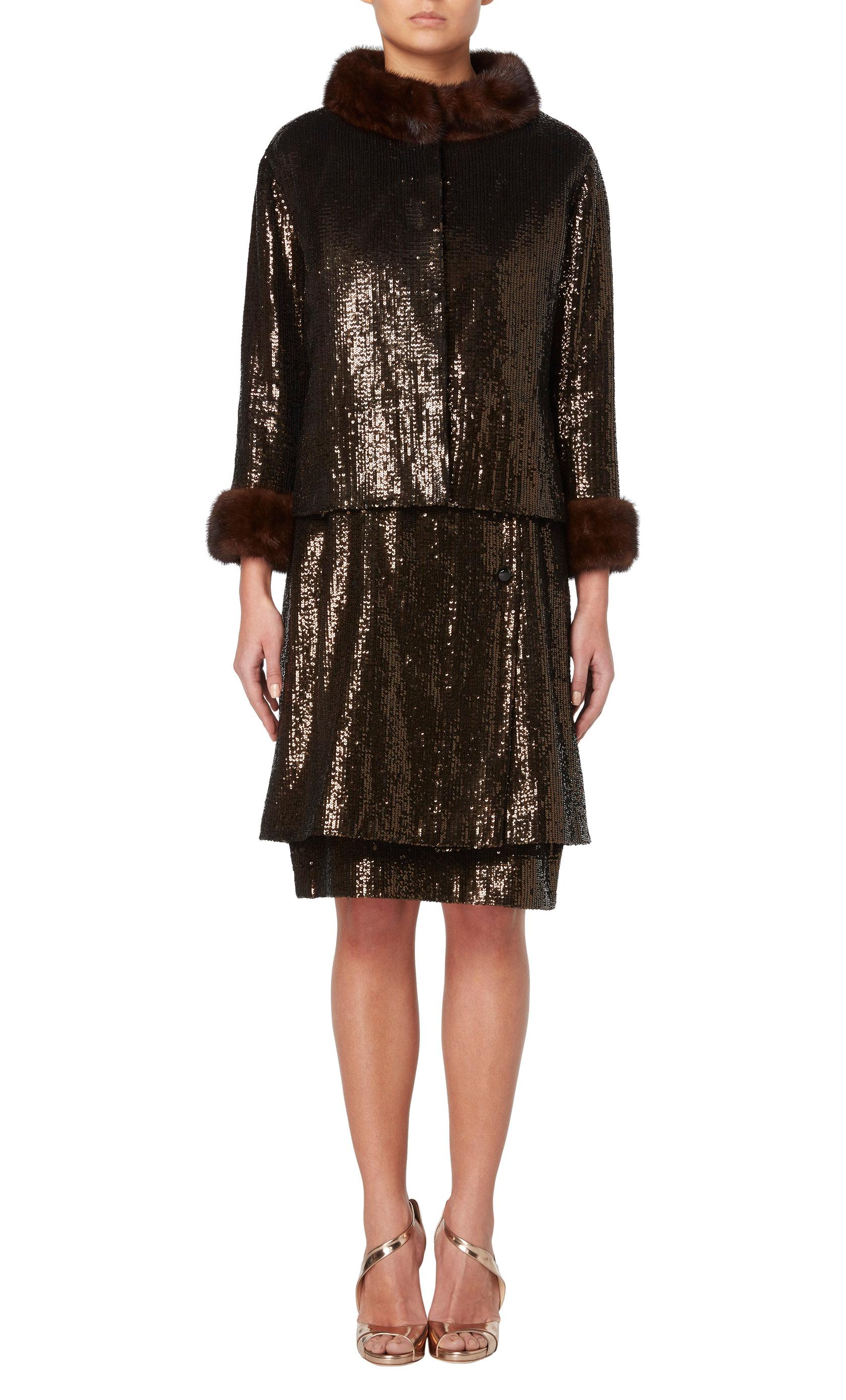 A stunning piece of haute couture, this Yves Saint Laurent suit is comprised of a jacket and sleeveless dress, both completely covered in brown sequins. The dress has a square neckline and double layer skirt, with decorative black faceted buttons to