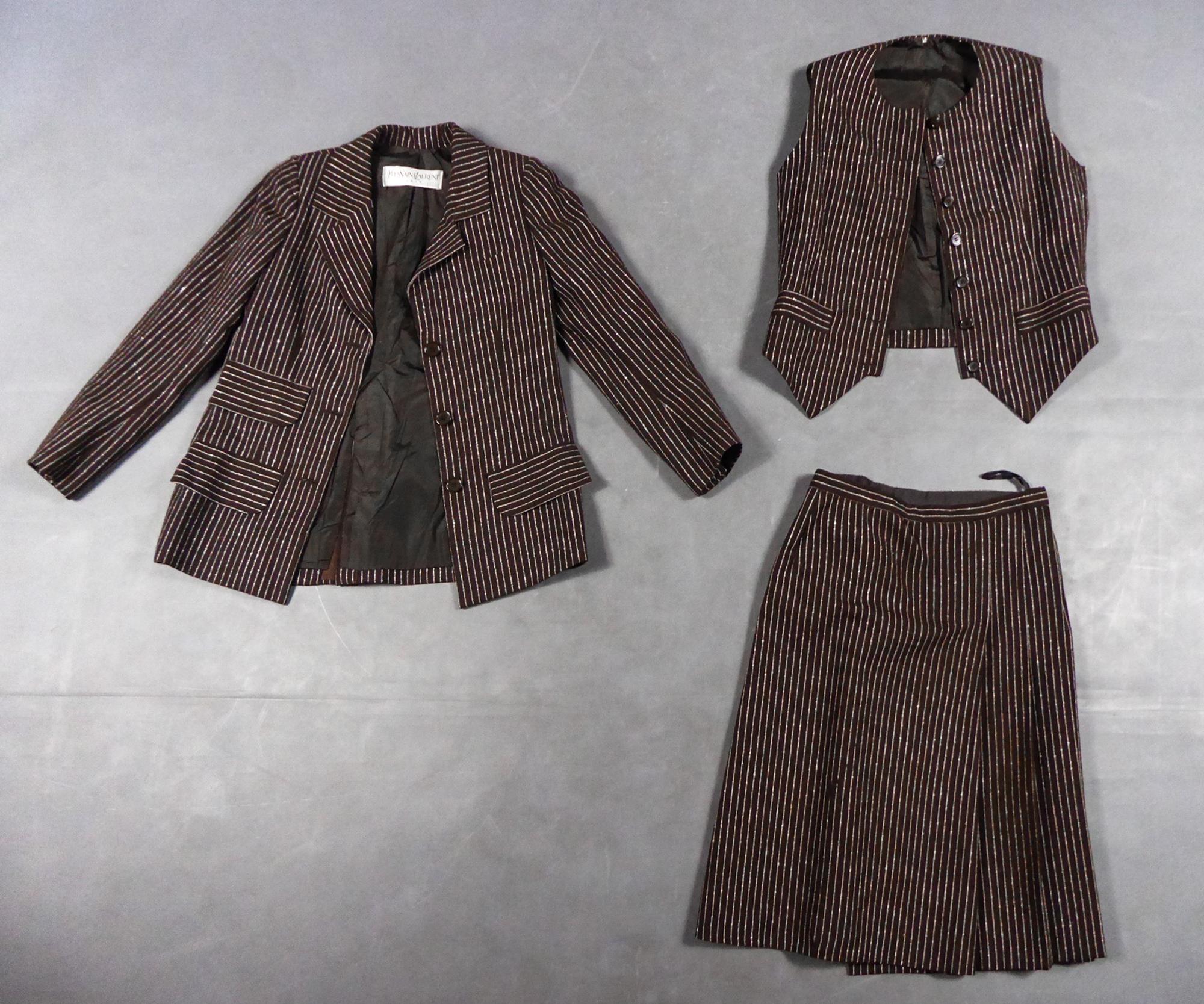 Circa 1967/1970 Francia 
Iconico tailleur con gonna a tre pezzi a righe sottili che fa da contraltare al famoso tailleur pantalone creato da Yves Saint Laurent nel 1967. Panno di lana color cioccolato intrecciato con sottili strisce arricciate color