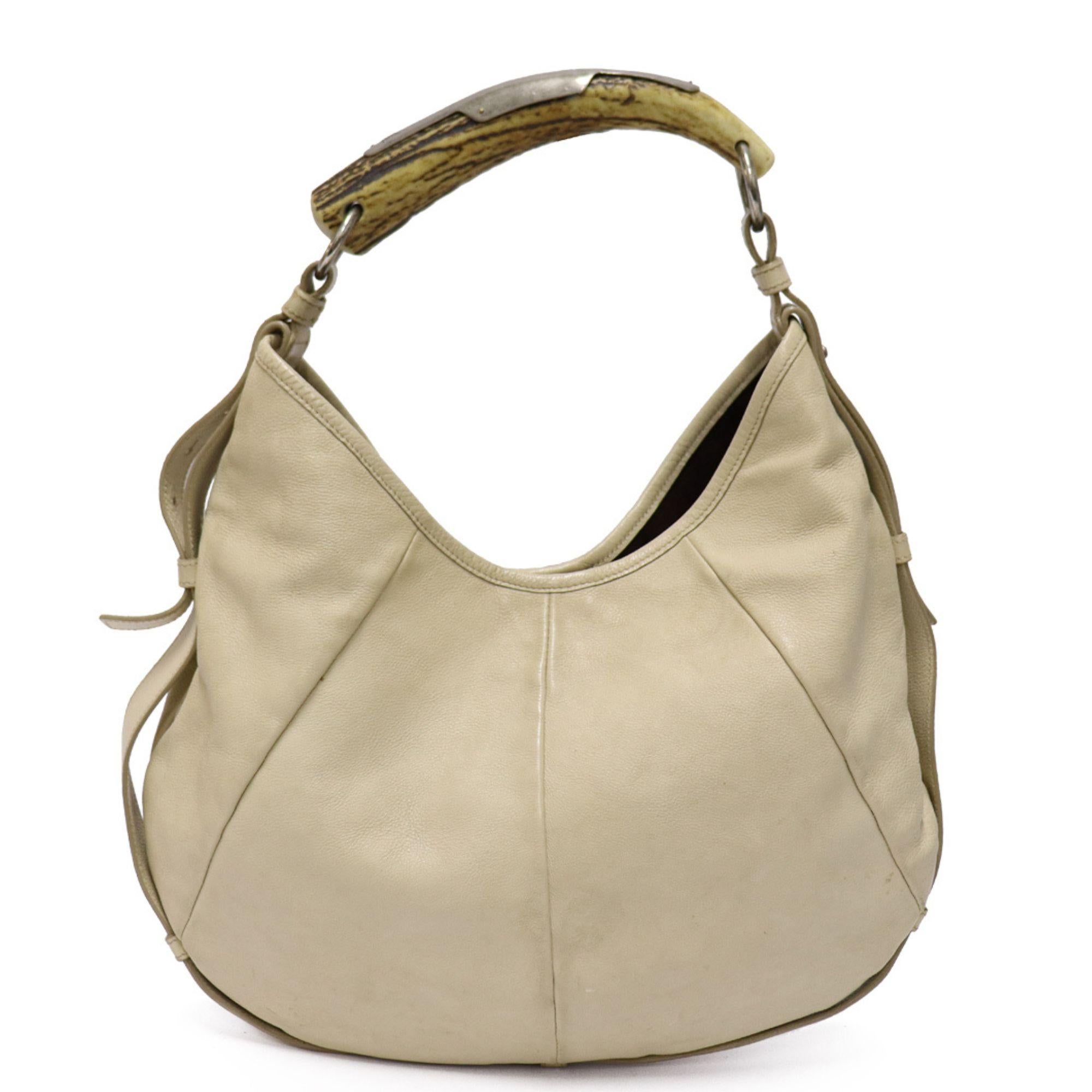 Designed by Tom Ford this bag features very soft and supple ivory leather. Features the iconic horn handle. Interior is spacious and contains one zipper compartment. Magnetic closure at top.

Measurements:
Height: 25cm
Width: 36cm
Depth: 2cm
Handle