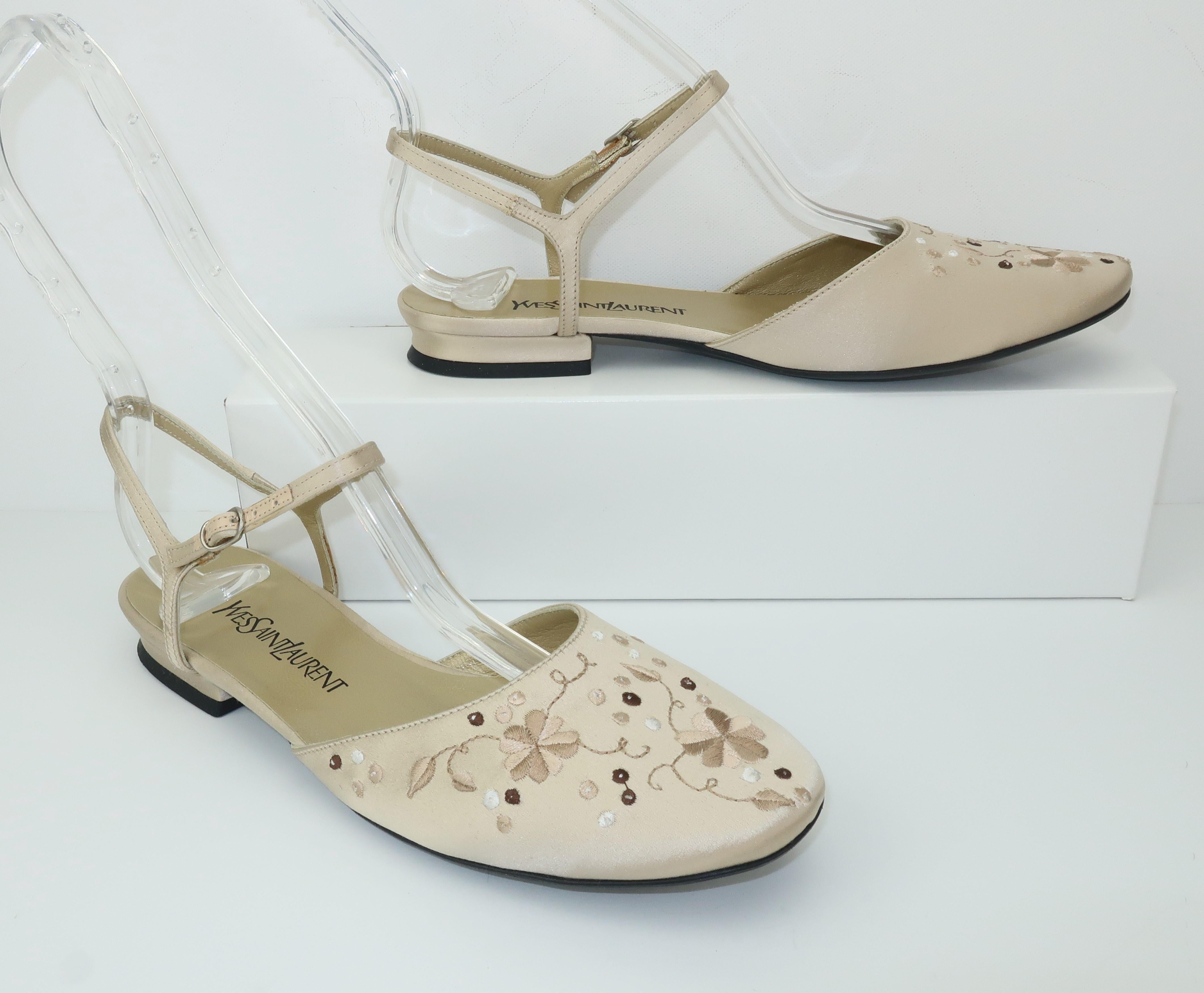 Yves Saint Laurent creates a flat ankle strap shoe in an ivory satin with beige and brown embroidered flowers accented by curling vines.  Lovely for day or evening wear.  Marked size 6 M with original box.  Excellent previously owned though never