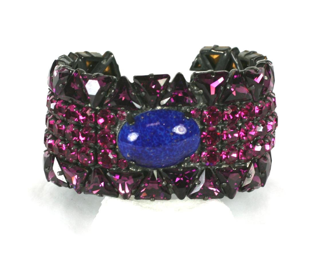 Yves Saint Laurent ornately jeweled cuff bracelet. Of vari cut fuschia and faux amythest glass stones with center focal oval cabochon of faux lapis pate de verre. Set in black japaned metal. Handmade by Maison Goossens for YSL.
Excellent Condition.