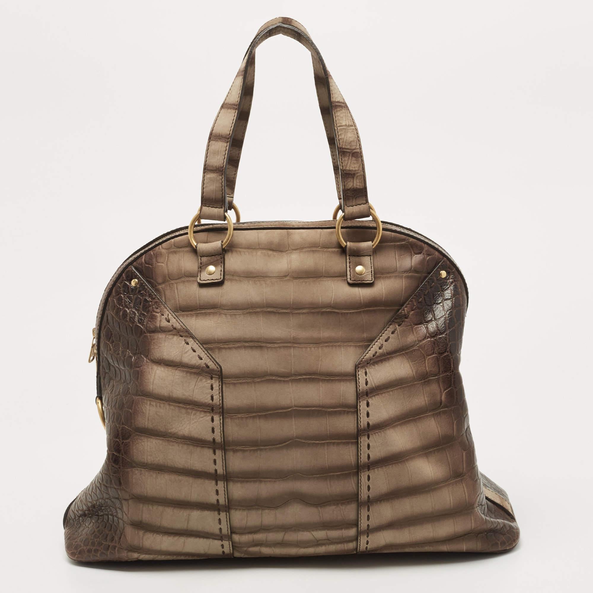 Complete an everyday look with this Yves Saint Laurent Muse bag. It has been crafted from croc-embossed leather and held by two handles. The bag has a zipper that leads to a spacious satin interior, and it is perfectly made whole by gold-tone