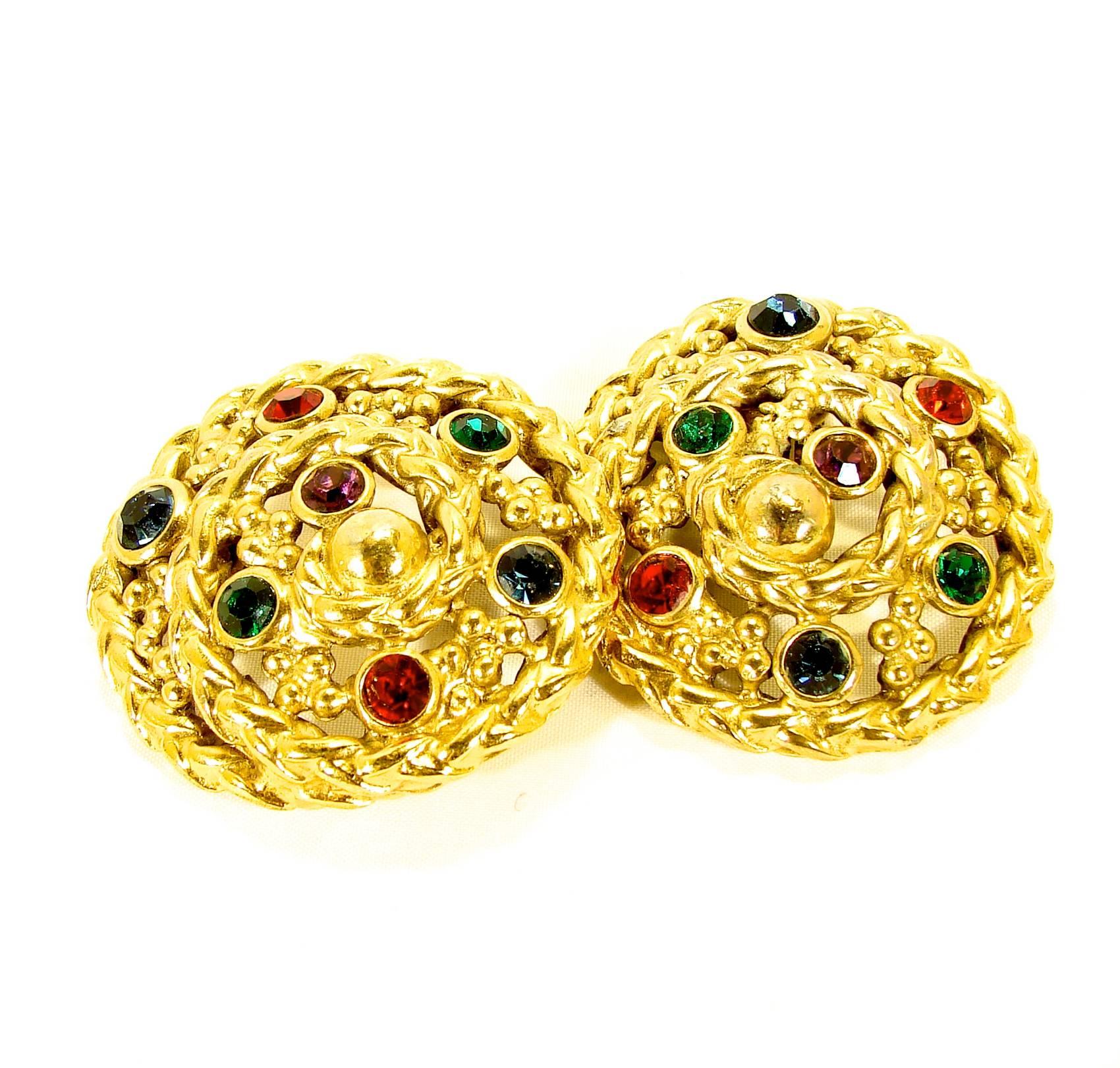 Delightful clip-style earrings were designed by Robert Goossens for Yves Saint Laurent circa the early 1970s.  These clip-style earrings feature small round glass cabs in shades of ruby, sapphire and emerald set in a gold rope setting. In excellent