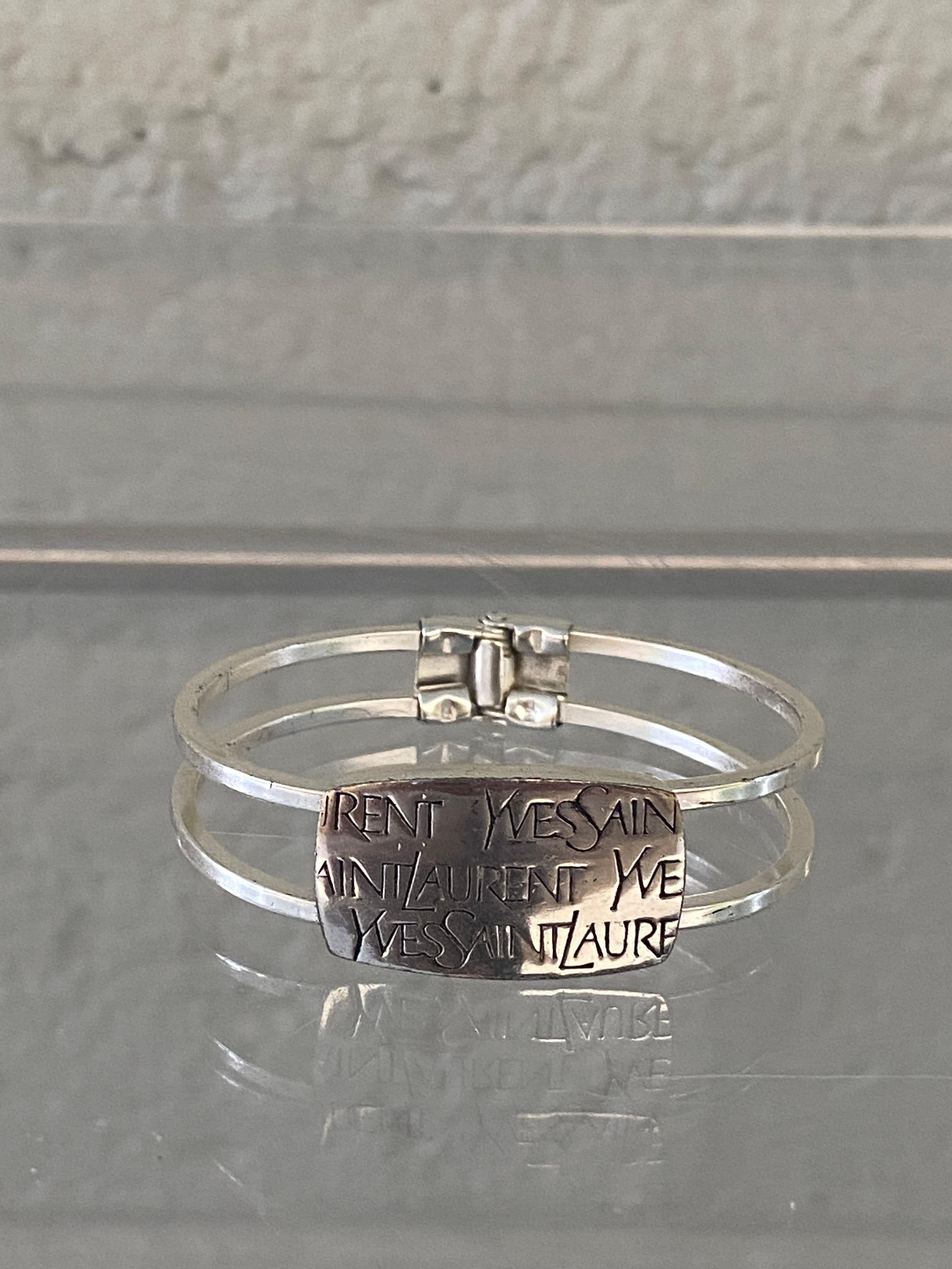 This collectable bangle bracelet from YSL collection is made to a fine finish using silver-tone metal. Logo's are in engraved. Classic statement piece.