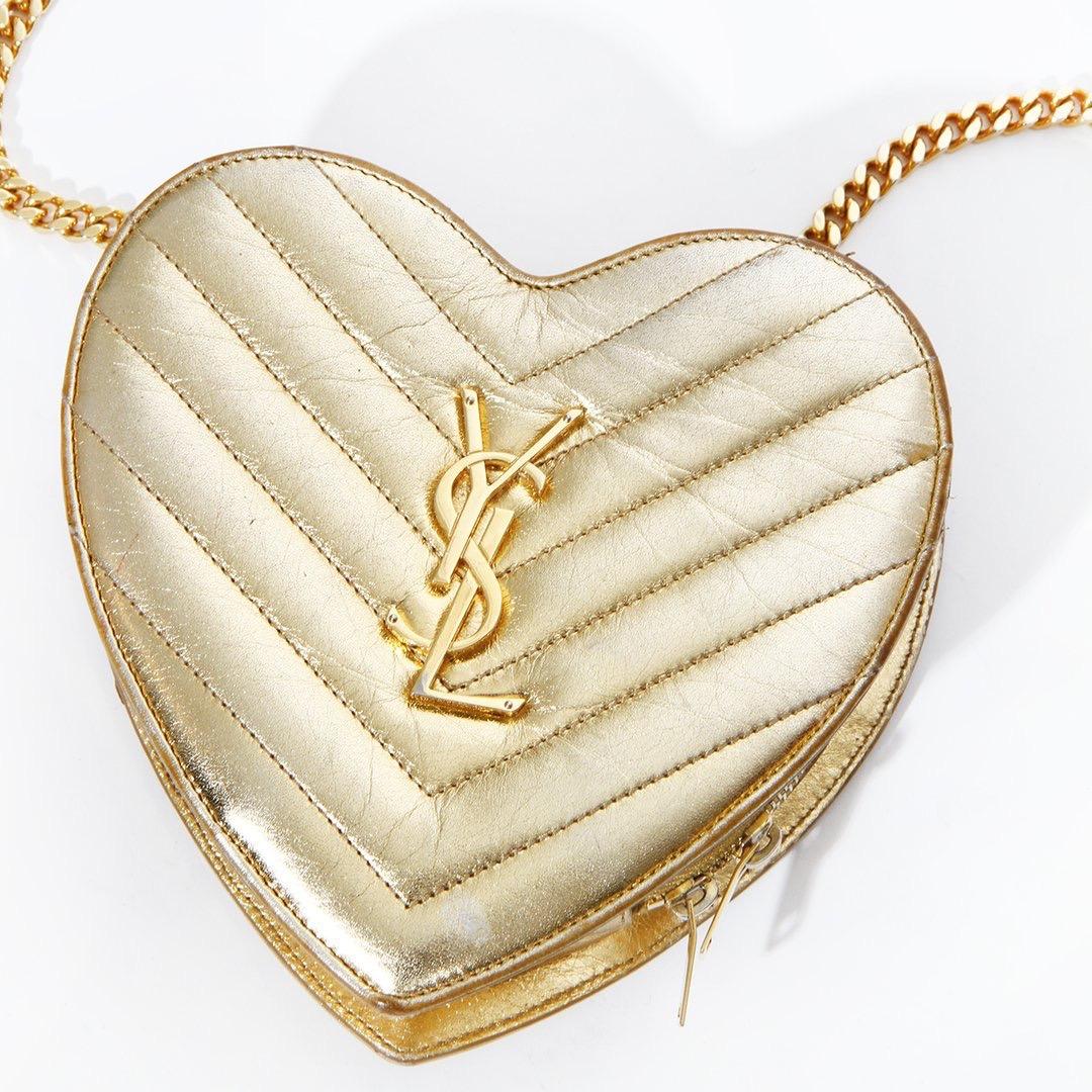 Product Details:
Matelasse Chevron Heart Bag by Saint Laurent 
Circa 2016
Chain strain with gold leather shoulder strap
Heart shaped
Metallic gold tone 
Matelasse (quilted) chevron design 
Zip top closure 
YSL logo on front
Black suede interior 
Can