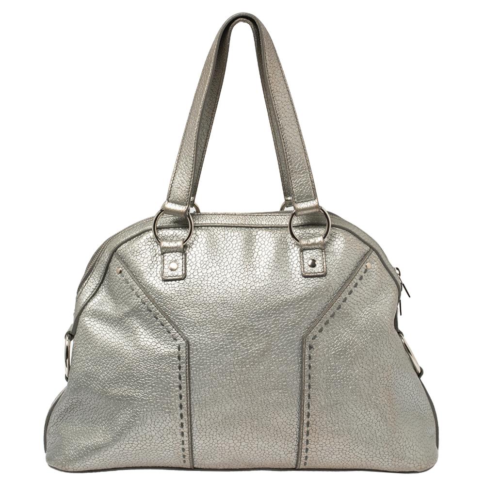 Get all the admiring glances when you step out swaying this Yves Saint Laurent Muse bag. It has been crafted in Italy from metallic silver leather and held by two top handles. The bag has a metal detail to the front and a spacious fabric interior