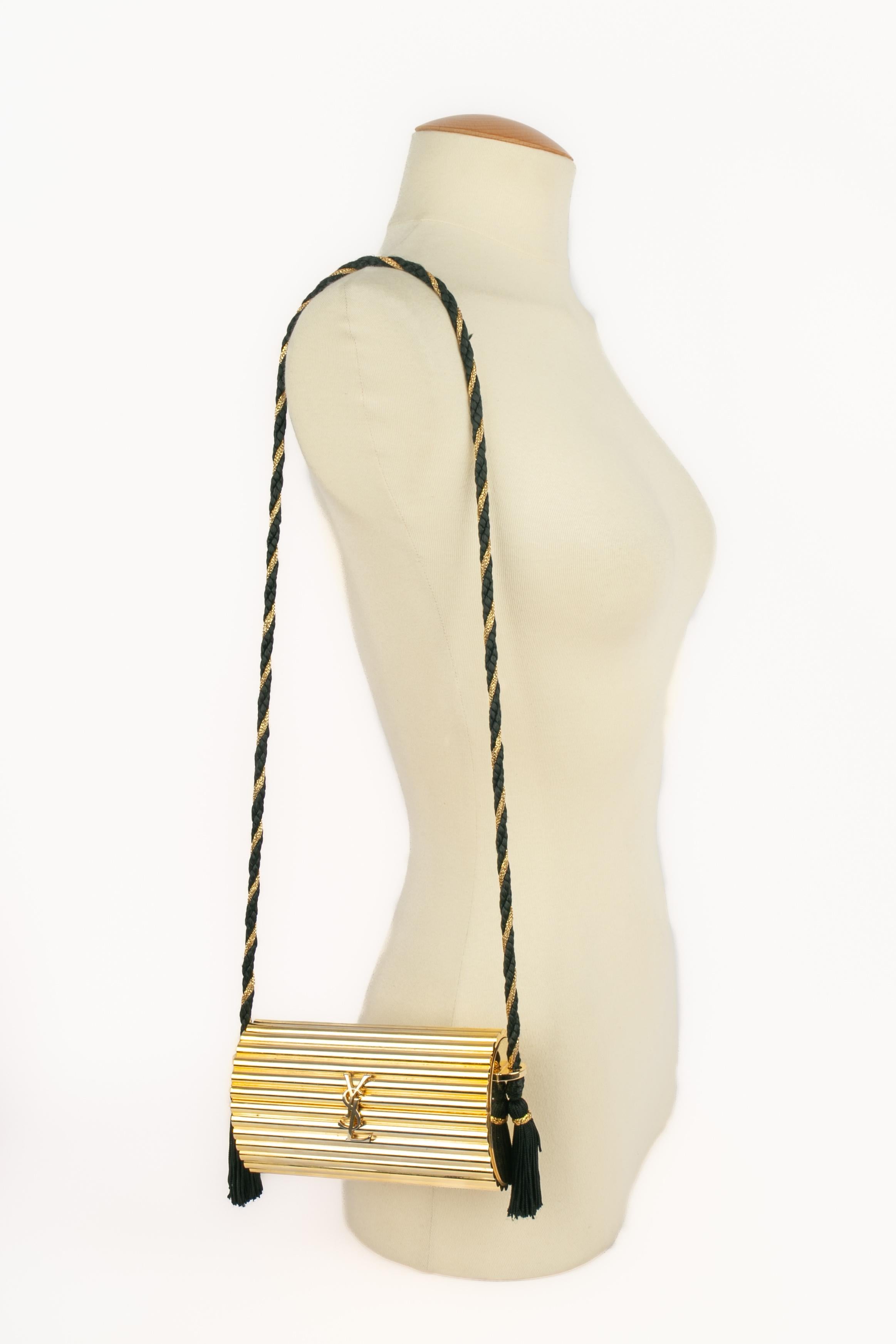 YVES SAINT LAURENT - Golden bakelite minaudiere bag with a golden and black trimming handle.

Condition:
Good condition

Dimensions:
Length: 15 cm - Height: 8 cm - Depth: 5.5 cm - Handle: 93 cm

SKU:S159
